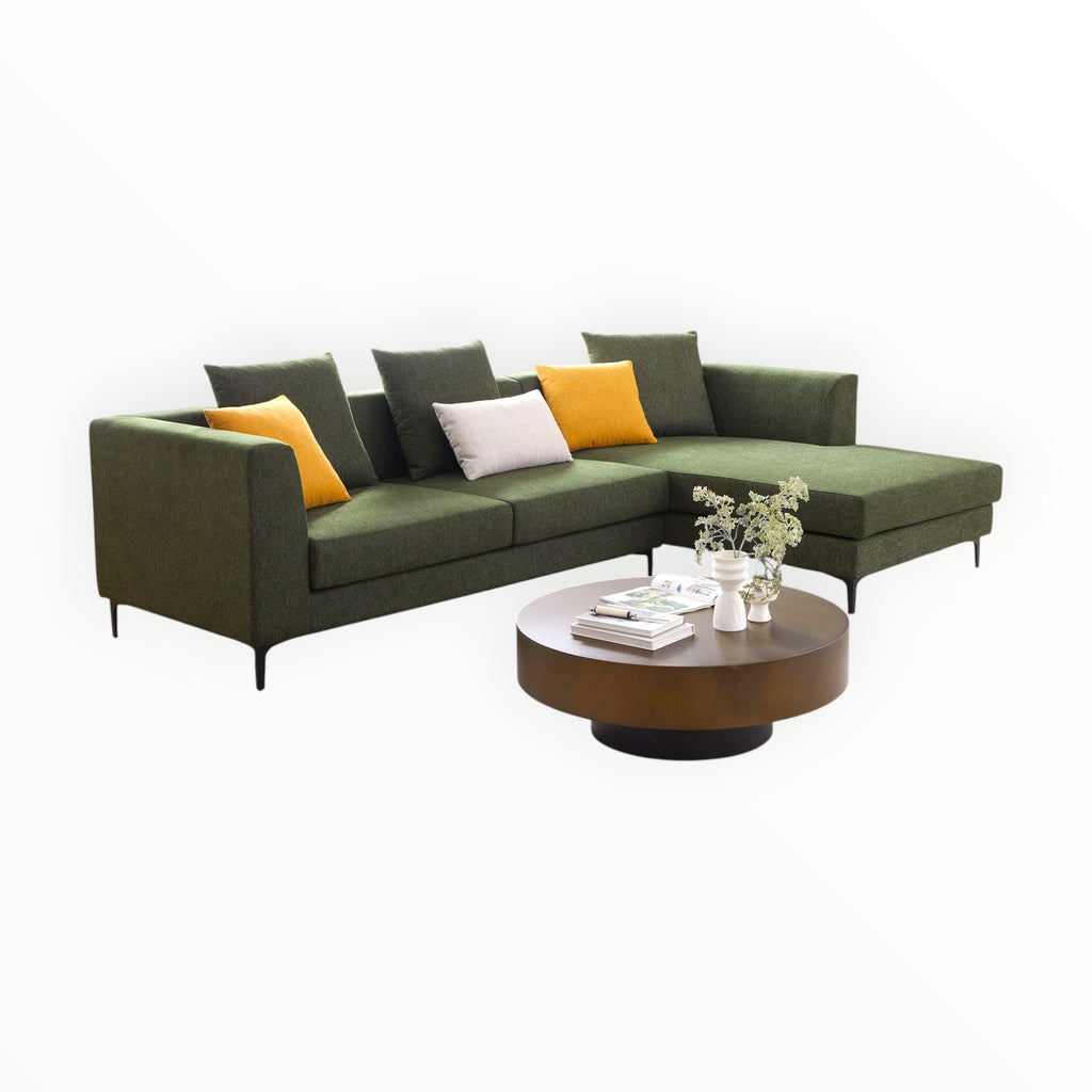 Green sectional sofa with colorful cushions and a wooden coffee table on a white background