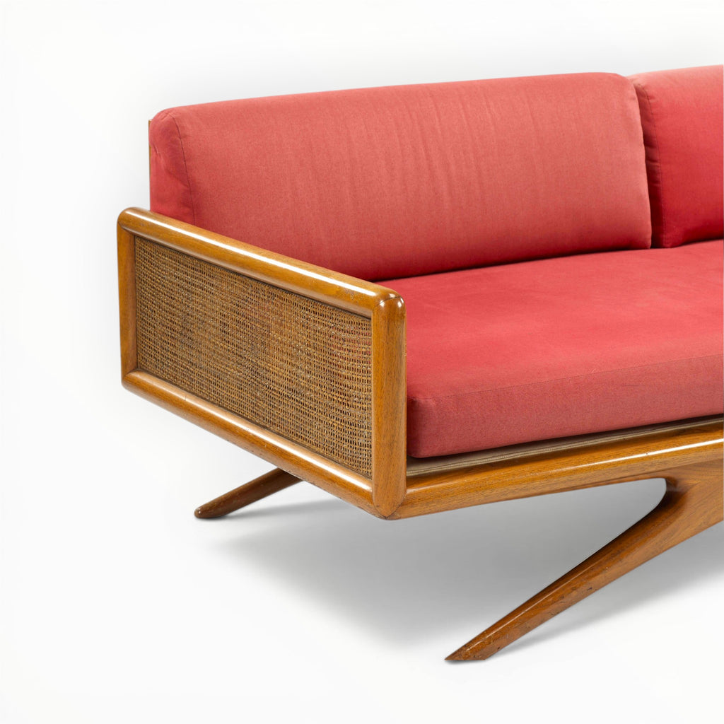 Red sofa with wooden frame and wicker backrest on a white background