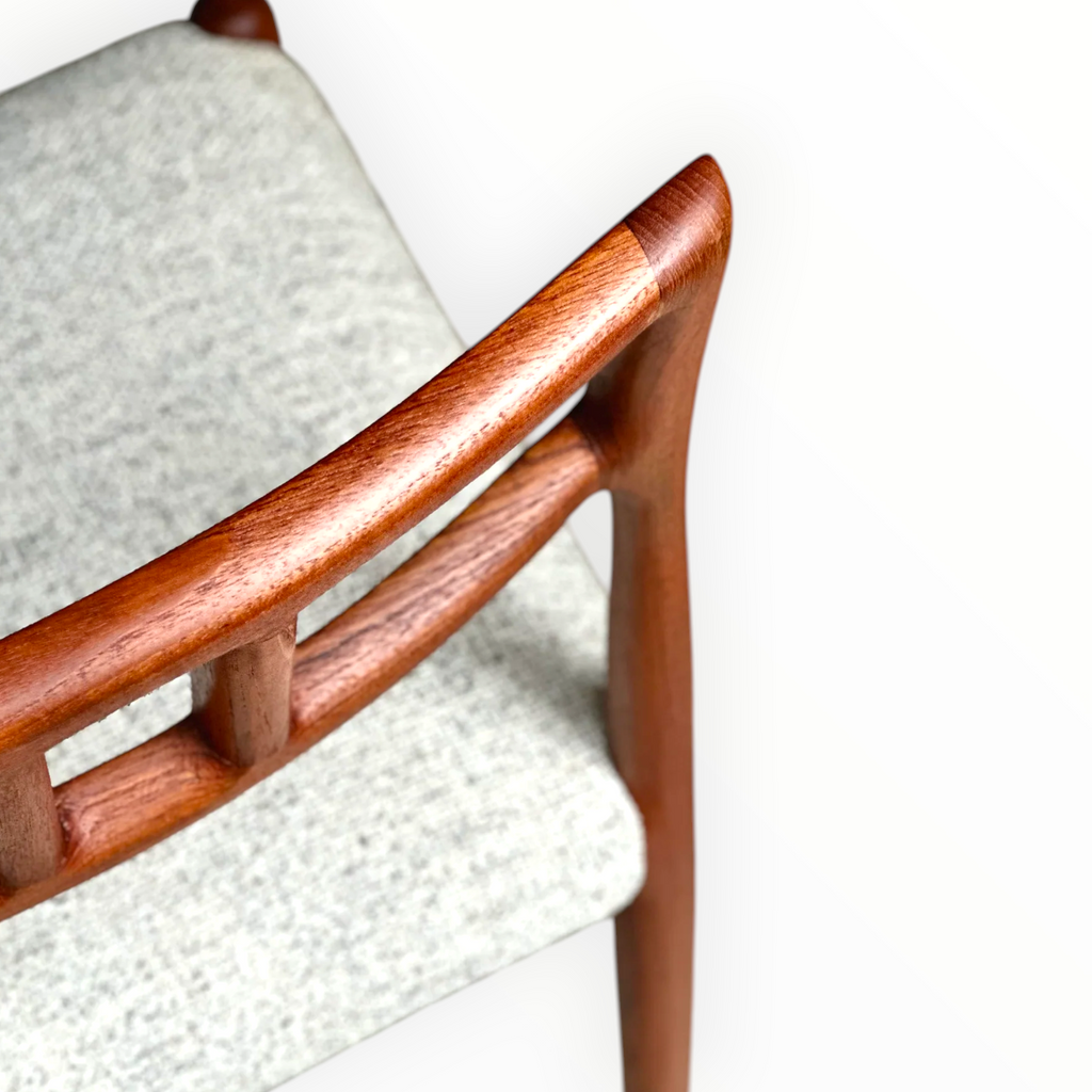 Close-up of a wooden chair with a white cushioned seat on a light background
