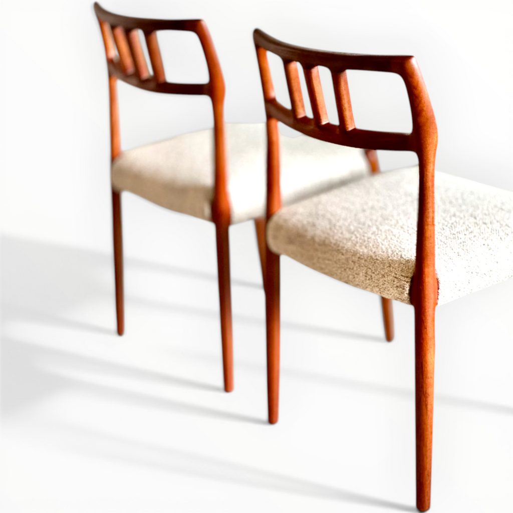 Two wooden chairs with beige cushioned seats on a white background