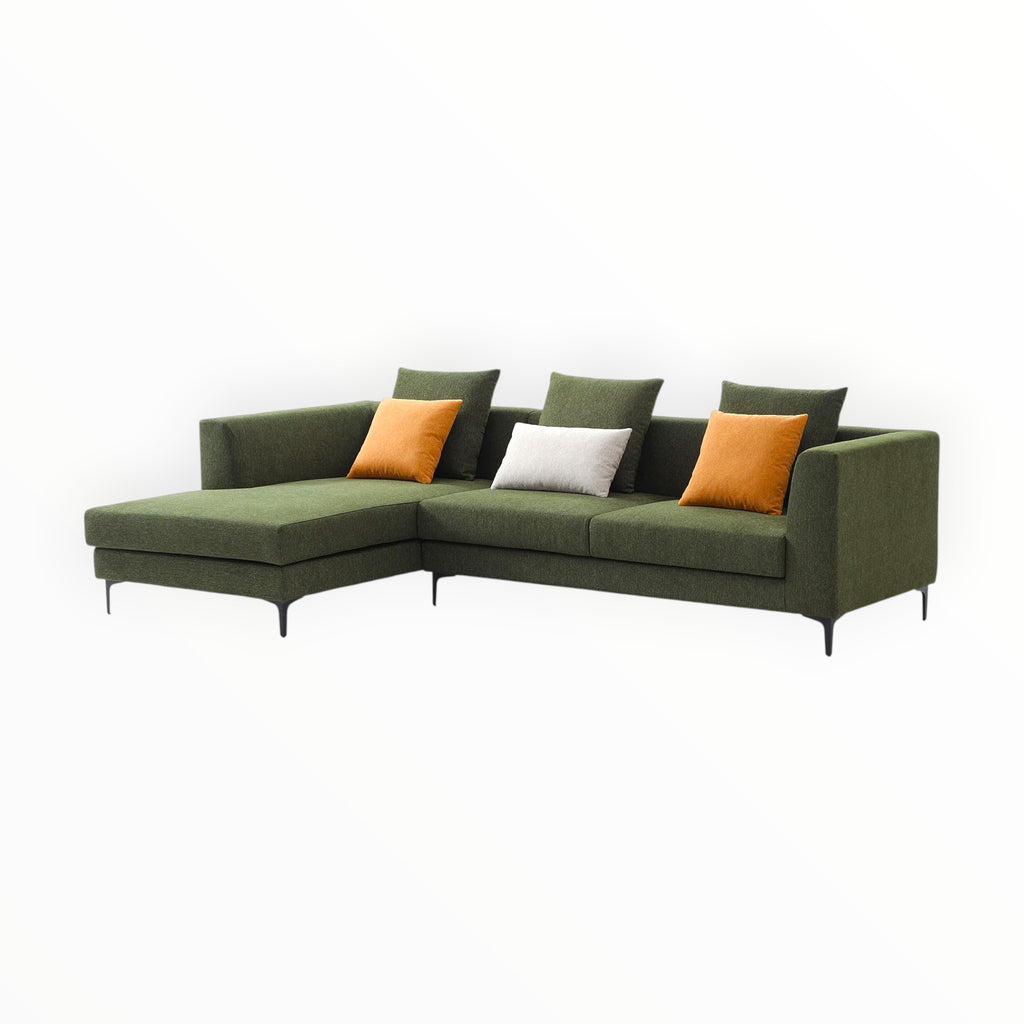 Green sectional sofa with orange and white cushions on a white background