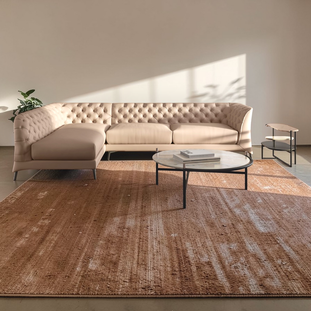 Beige tufted sofa in a modern living room with a patterned rug and coffee table.