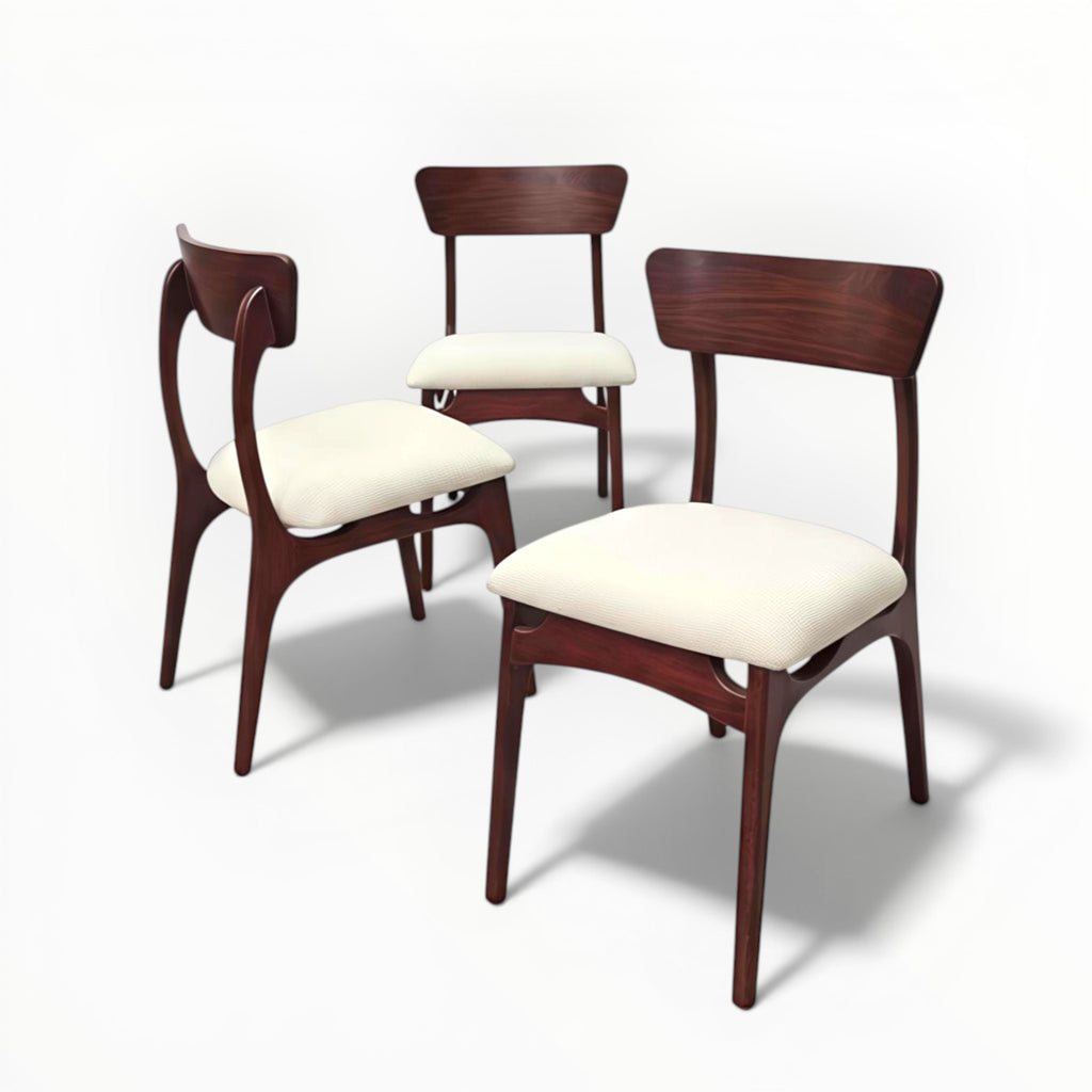 Three wooden chairs with white cushions on a white background