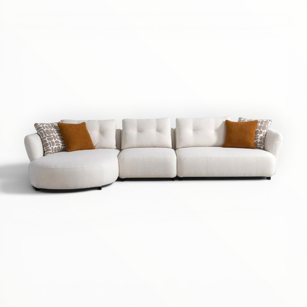 White sectional sofa with patterned and brown cushions on a white background