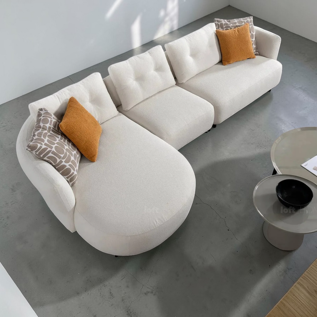 White sectional sofa with orange and patterned throw pillows in a modern living room.