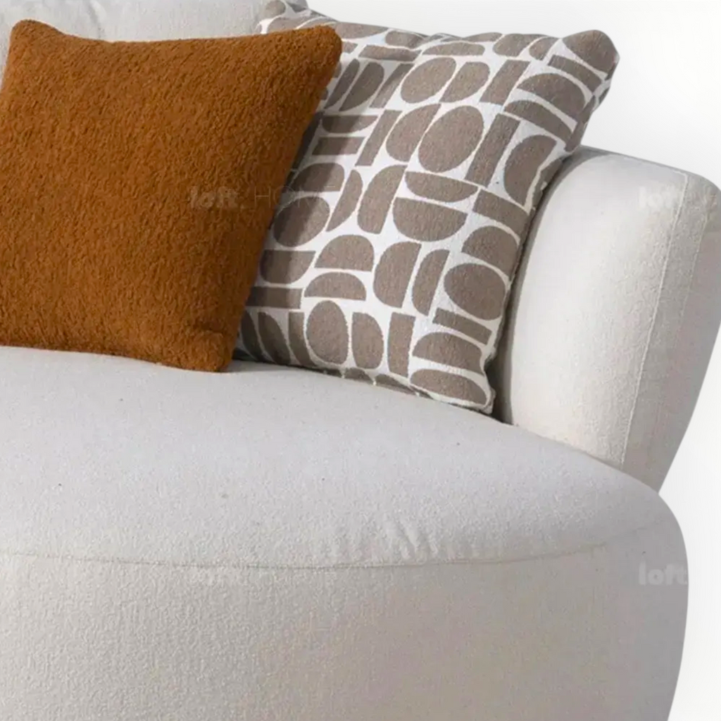 Two pillows, one brown and one with a geometric pattern, on a white sofa.