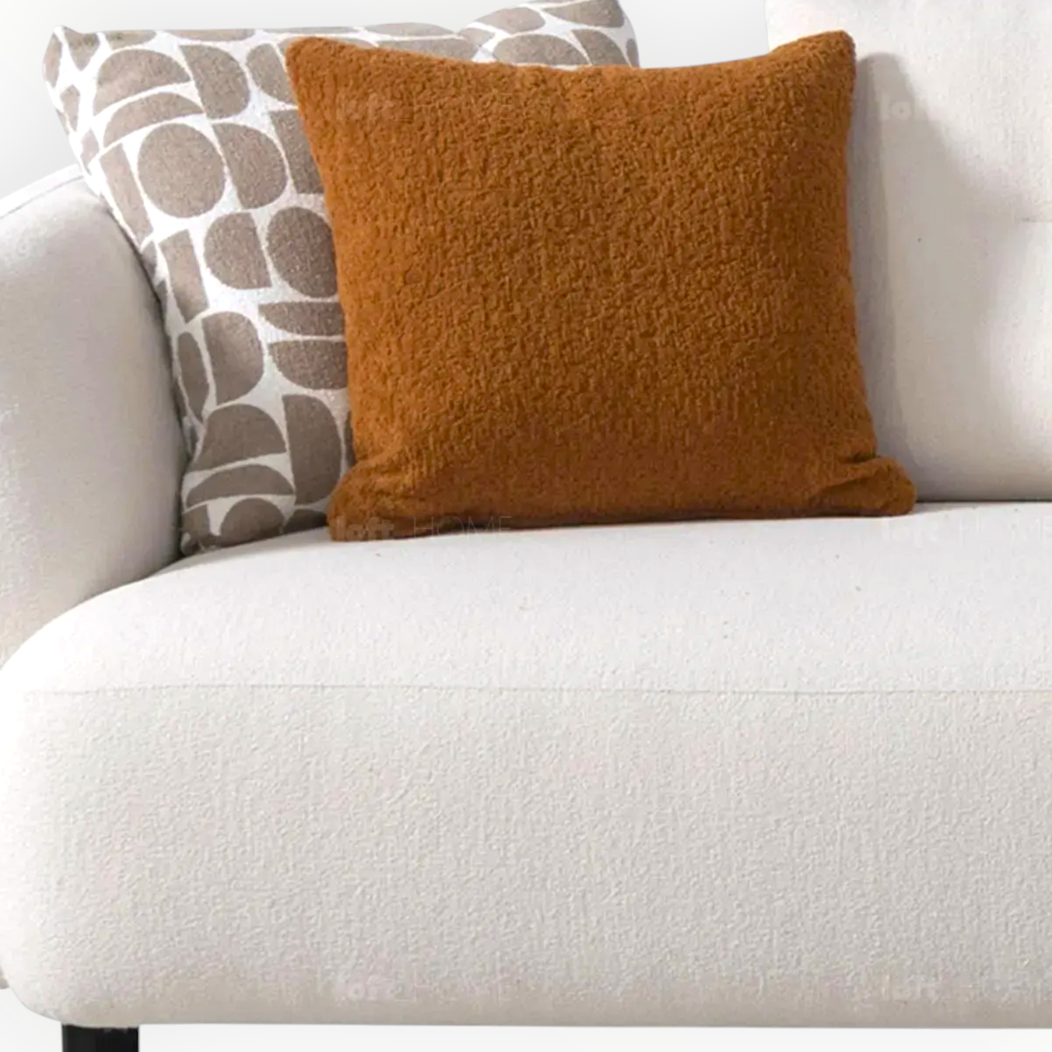 Brown textured pillow on a white couch with another patterned pillow.