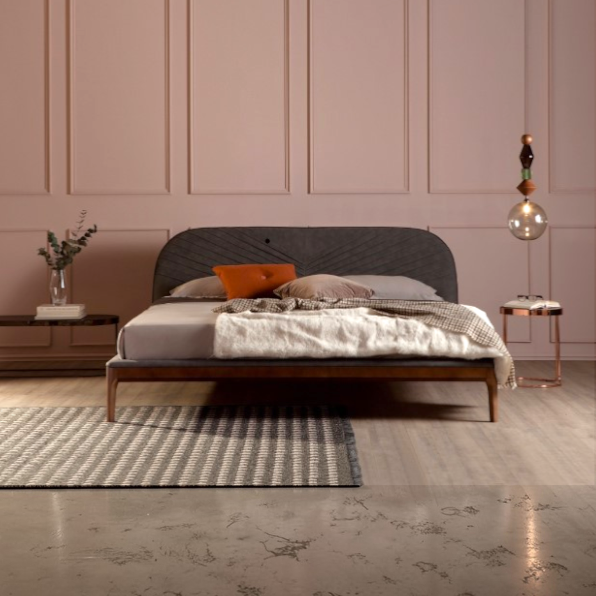 Bedroom with a bed against a pink paneled wall, featuring a rug and side tables.