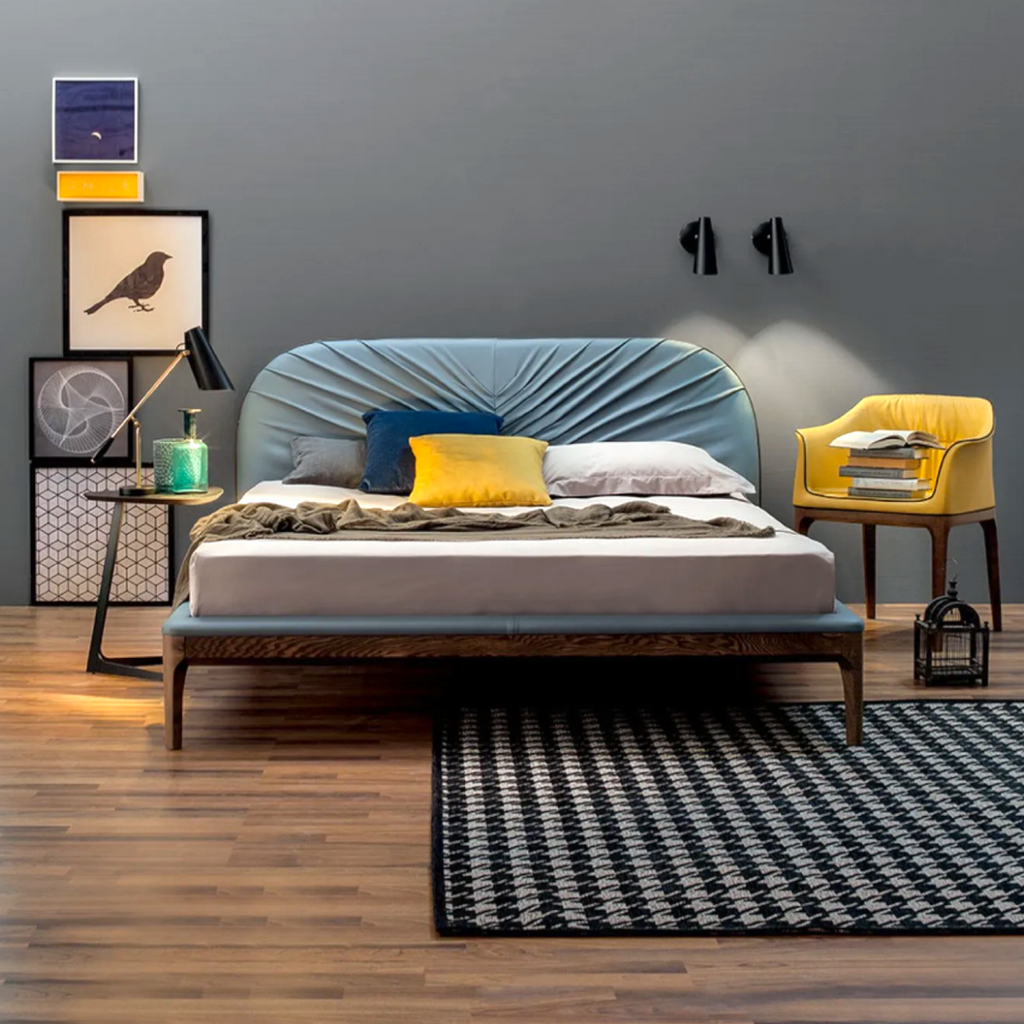 Modern bedroom with a blue upholstered bed, yellow chair, and decorative elements.