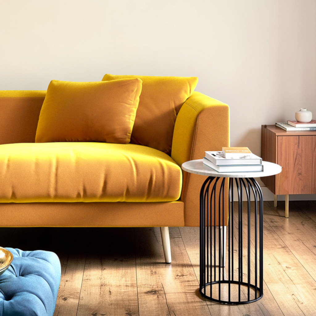 Yellow sofa in a living room with a black side table and books.