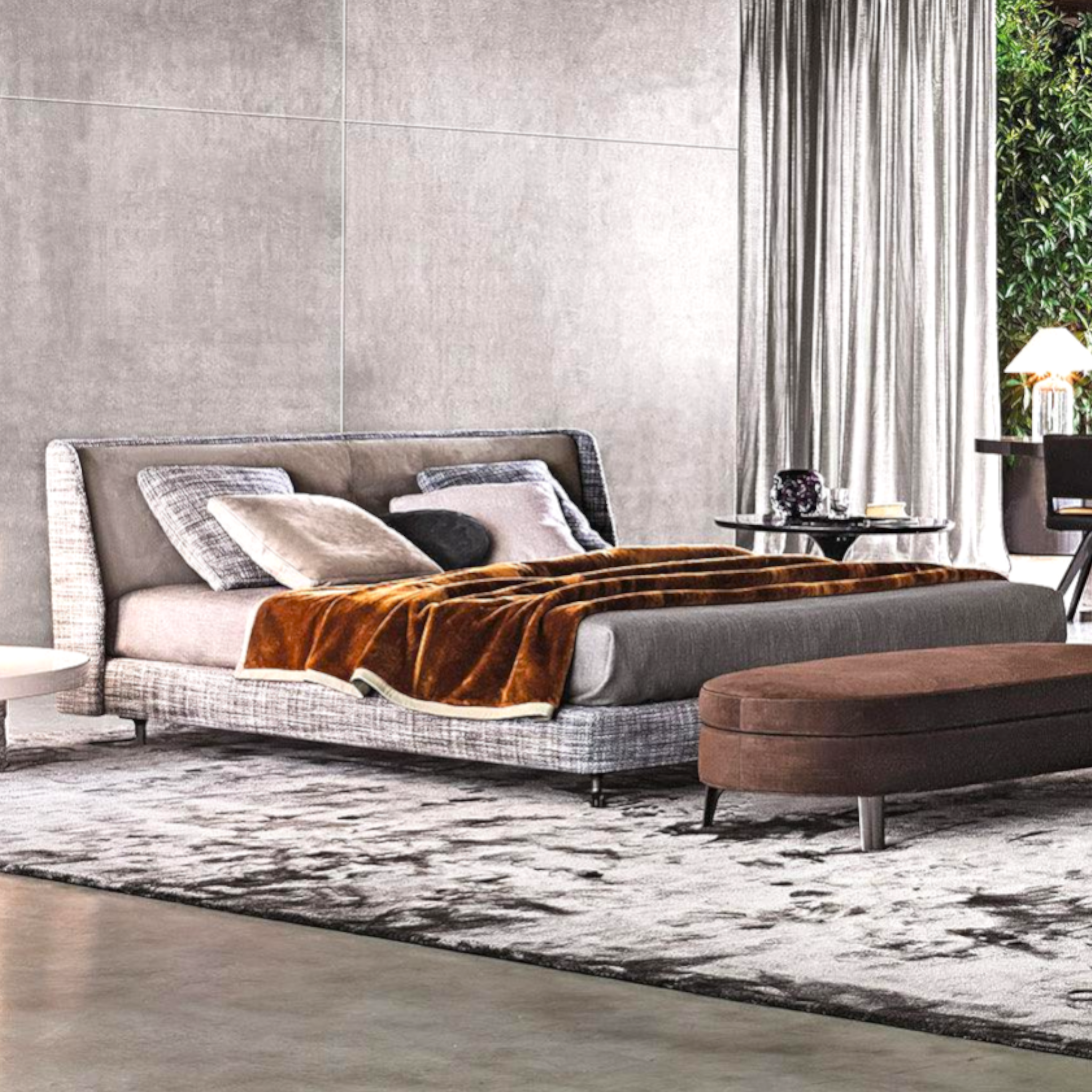 Modern bedroom with a gray upholstered bed and brown ottoman.