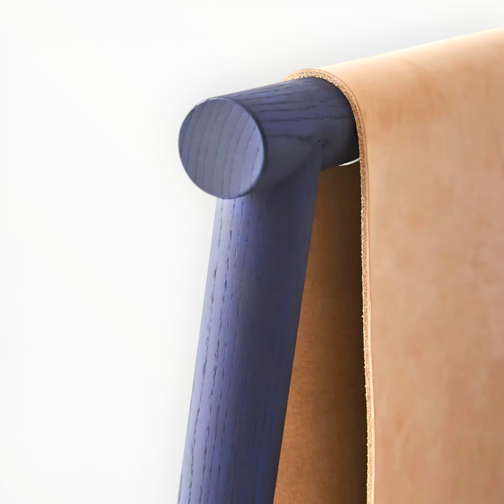 Close-up of a blue wooden leg and brown leather armrest of a chair.