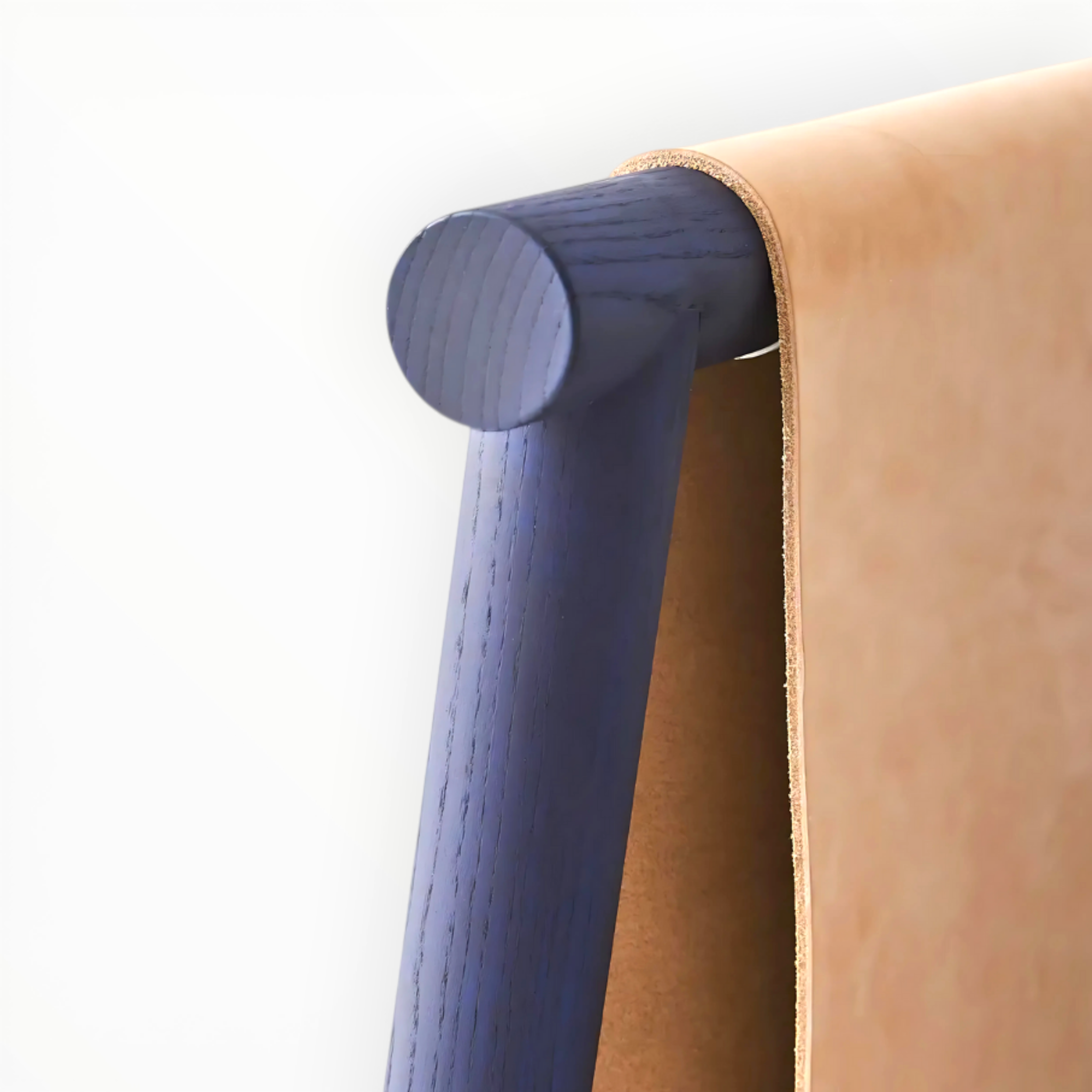 Close-up of a blue wooden leg and brown leather armrest of a chair.