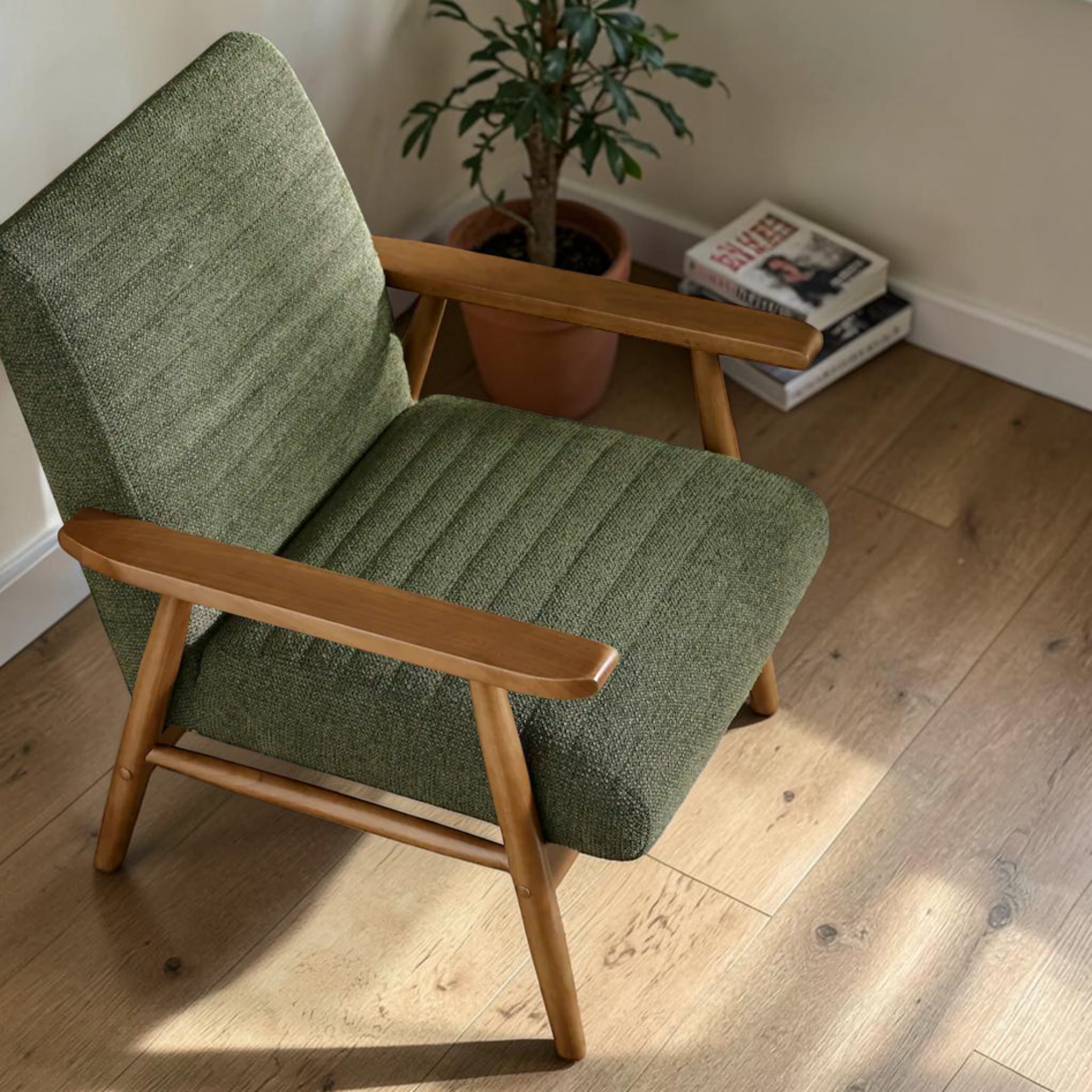 Green armchair with wooden arms and legs on a wooden floor.