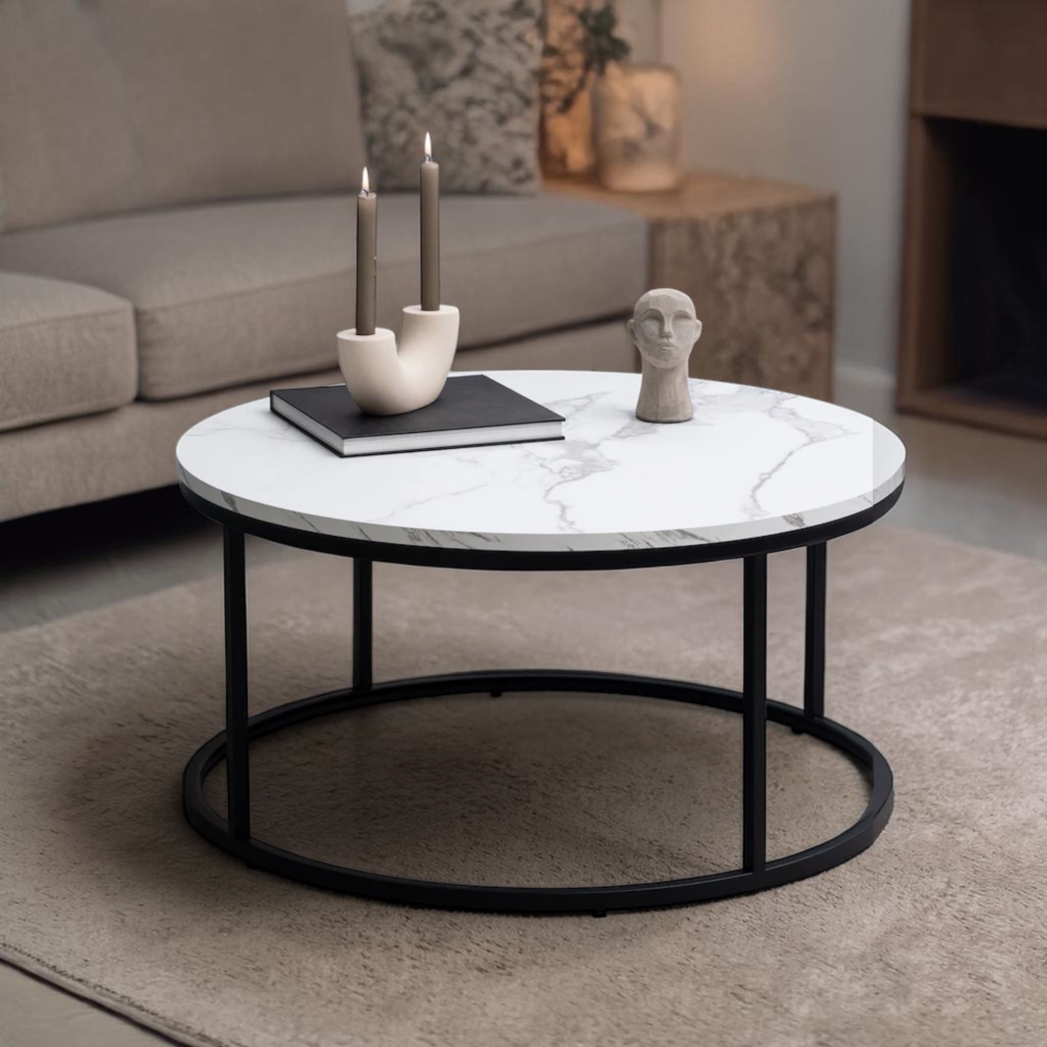 Round marble coffee table with black metal base in a living room setting.