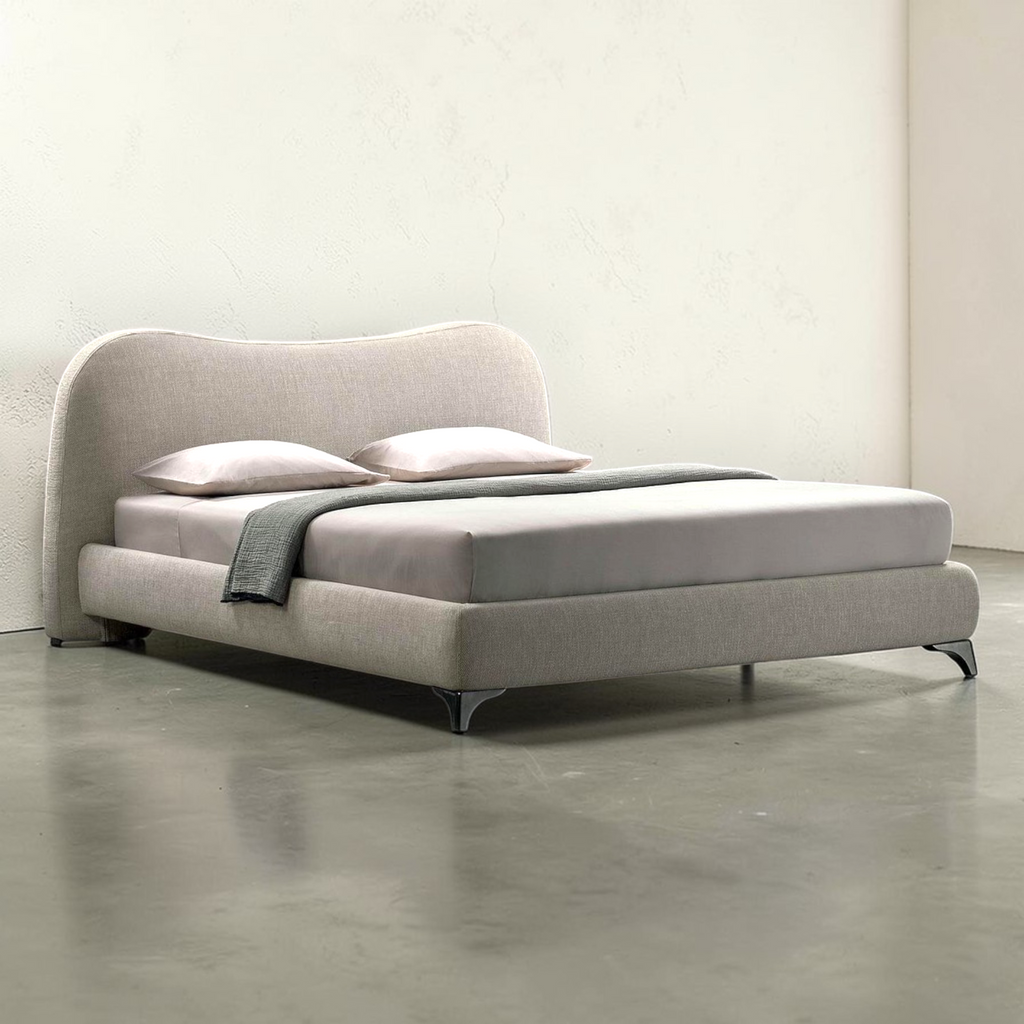 Modern gray bed with a headboard and pillows on a concrete floor.