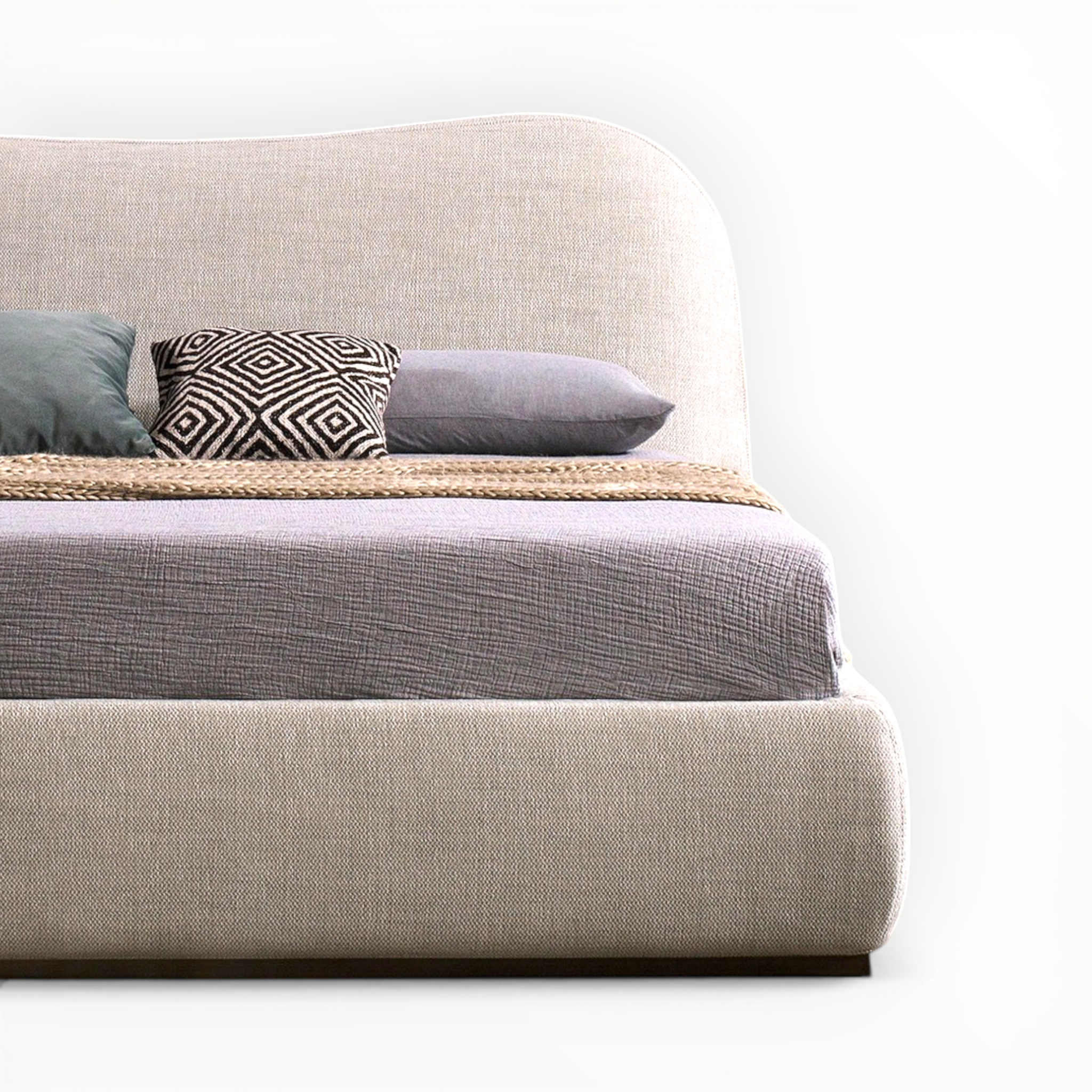 Beige upholstered bed with gray bedding and patterned pillow on a white background