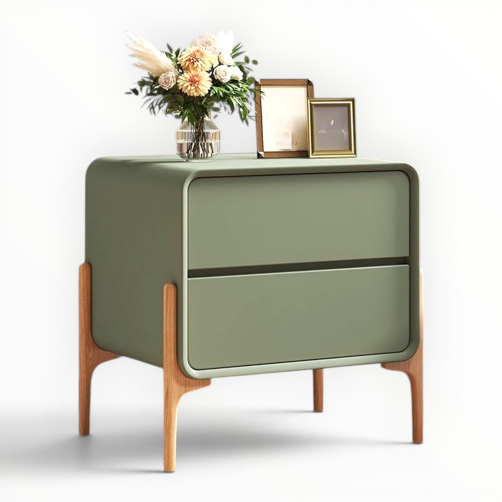 Green side table with wooden legs holding a vase of flowers and picture frames on a white background