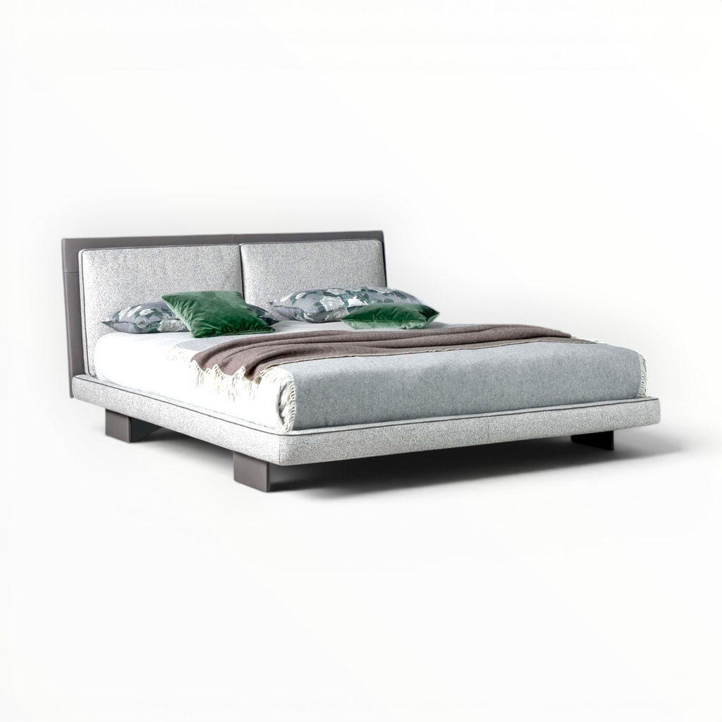 Modern bed with gray upholstered headboard and white bedding on a white background