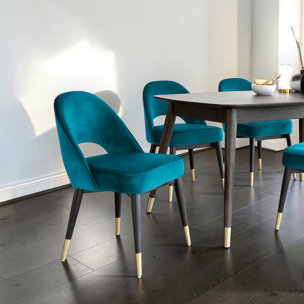 Teal chairs with gold legs around a wooden dining table in a modern room.