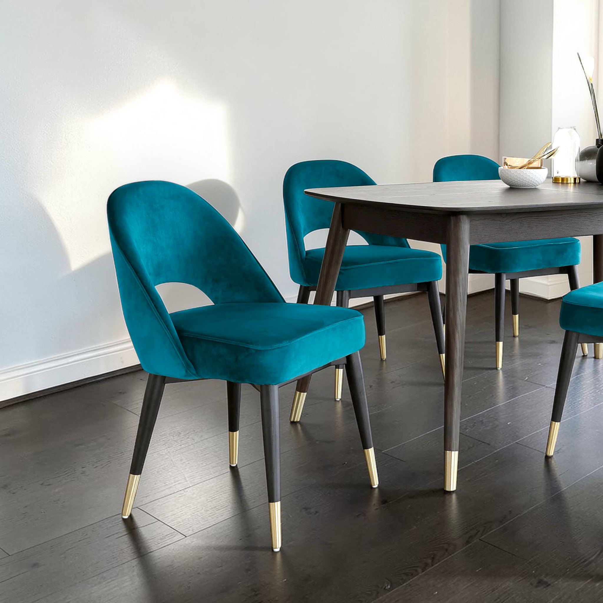 Teal chairs with gold legs around a wooden dining table in a modern room.