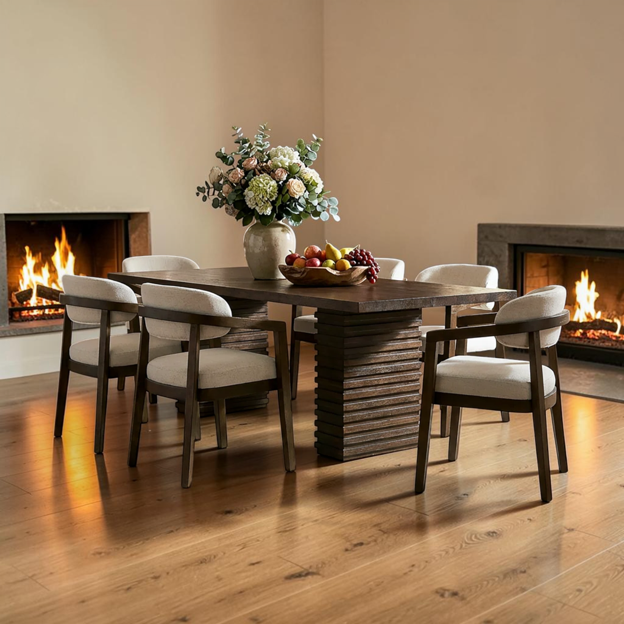 Dining room with a wooden table and chairs, flowers, and fruit in front of a fireplace.