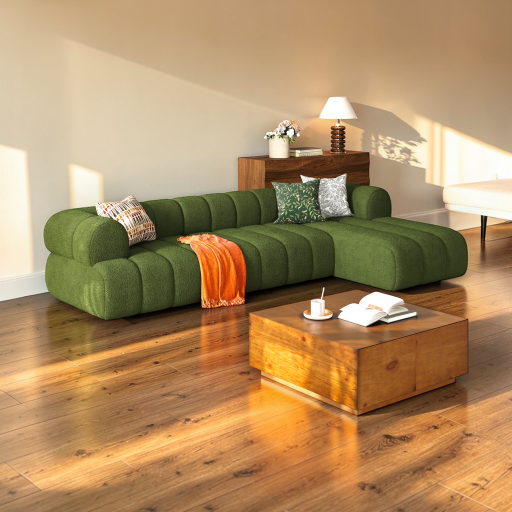 Green sectional sofa in a living room with wooden coffee table and decorative items.