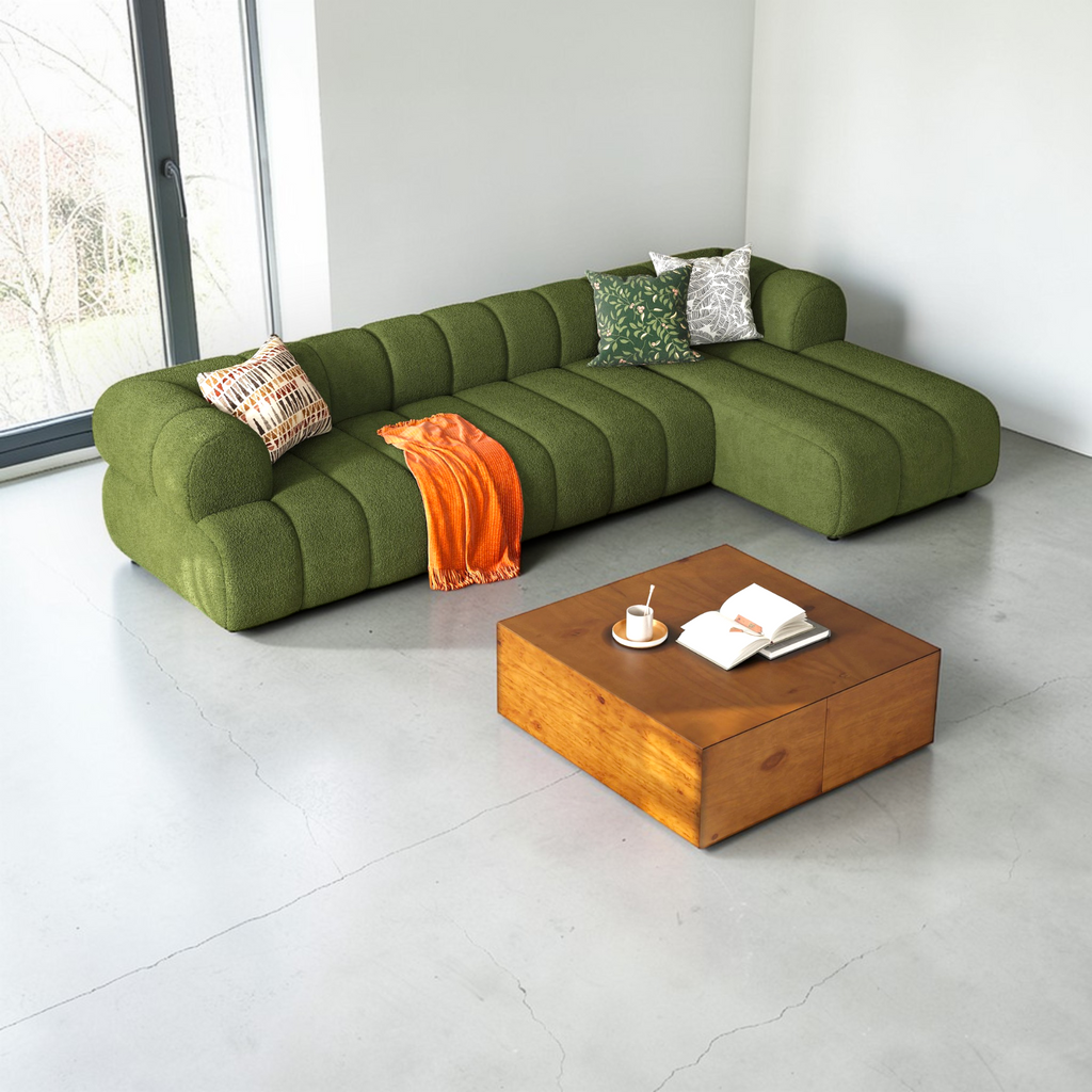 Green sectional sofa with a wooden coffee table in a modern living room.