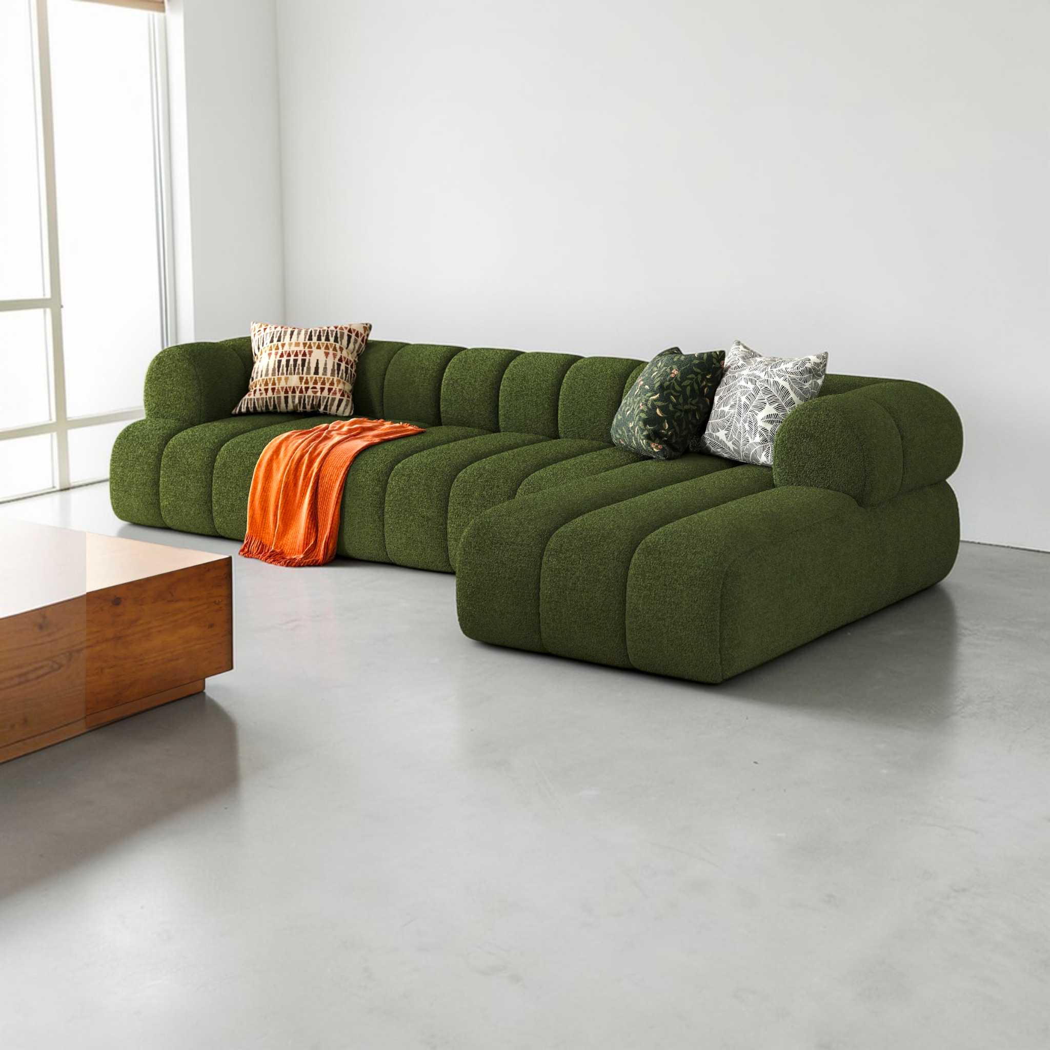 Green sofa with decorative pillows and a blanket in a modern living room.