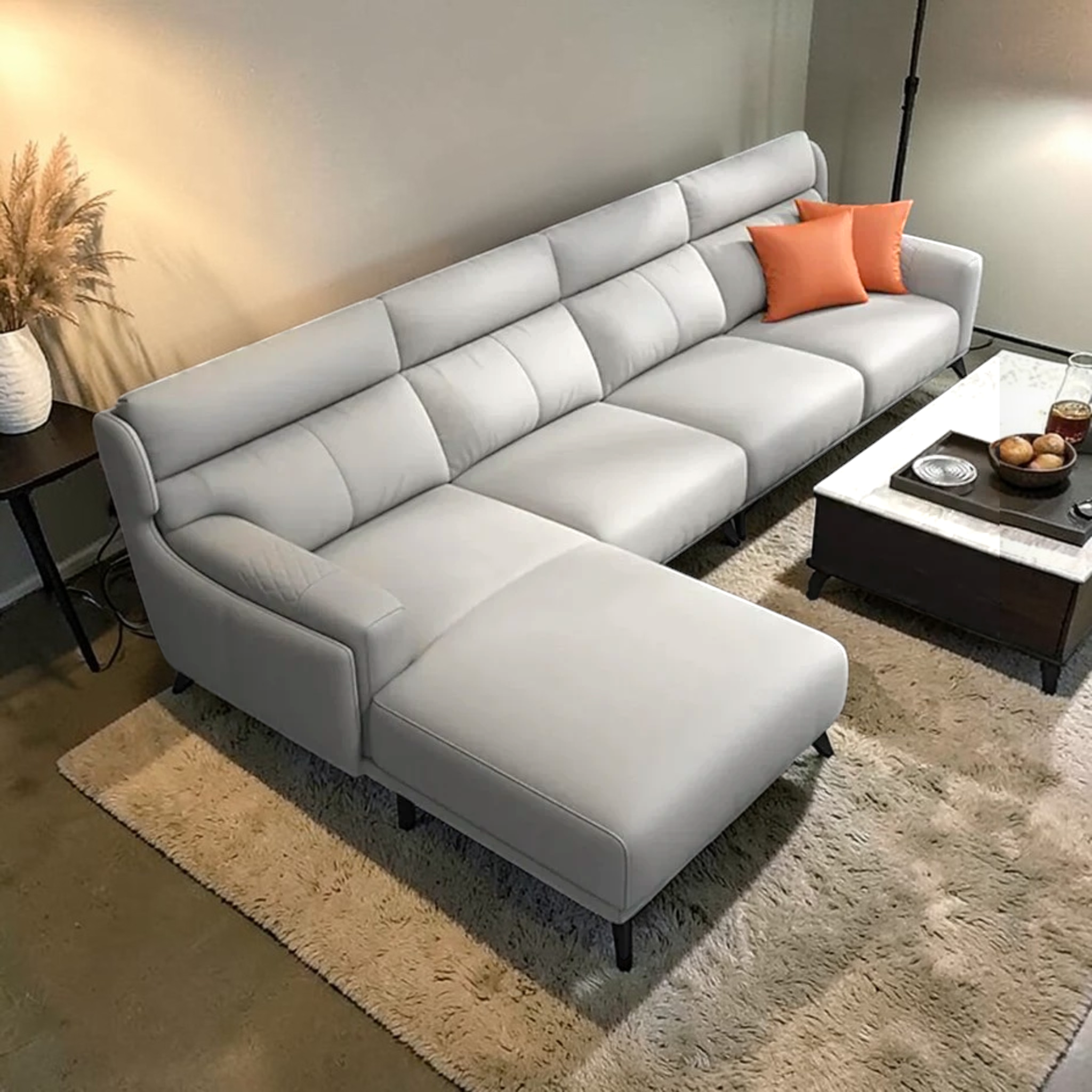 Gray sectional sofa with orange pillows in a living room setting.