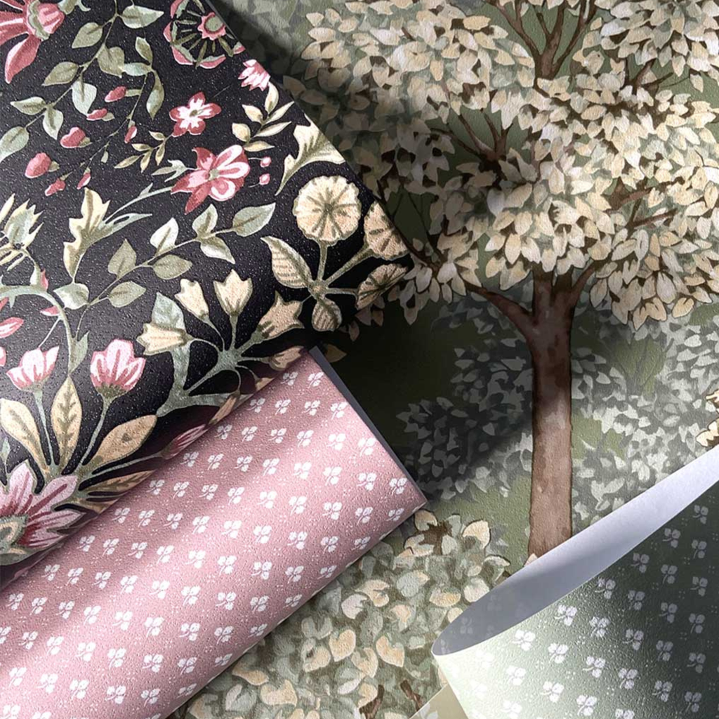 Three rolls of floral-patterned fabric on a textured surface with a tree design.