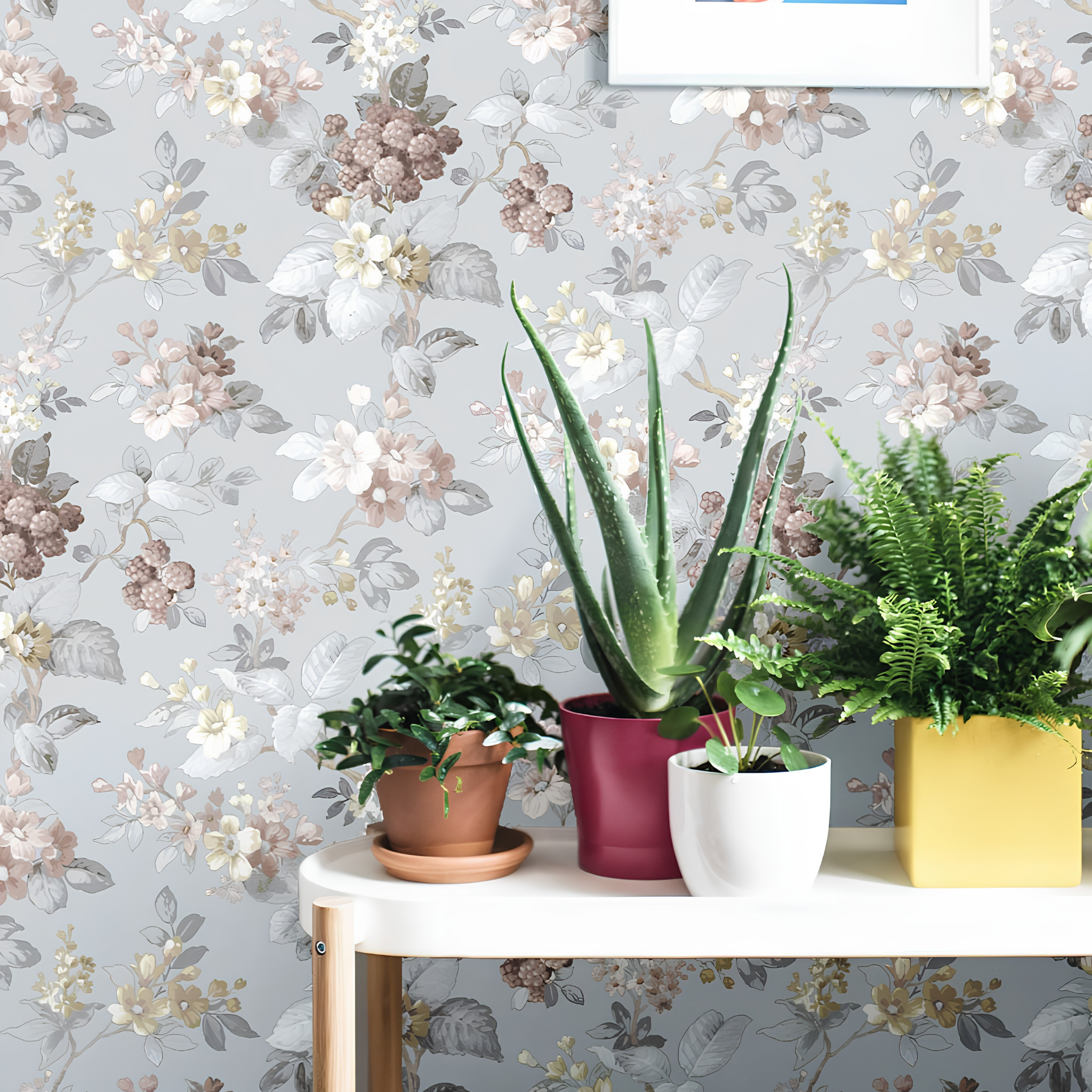 Potted plants on a table with floral wallpaper in the background