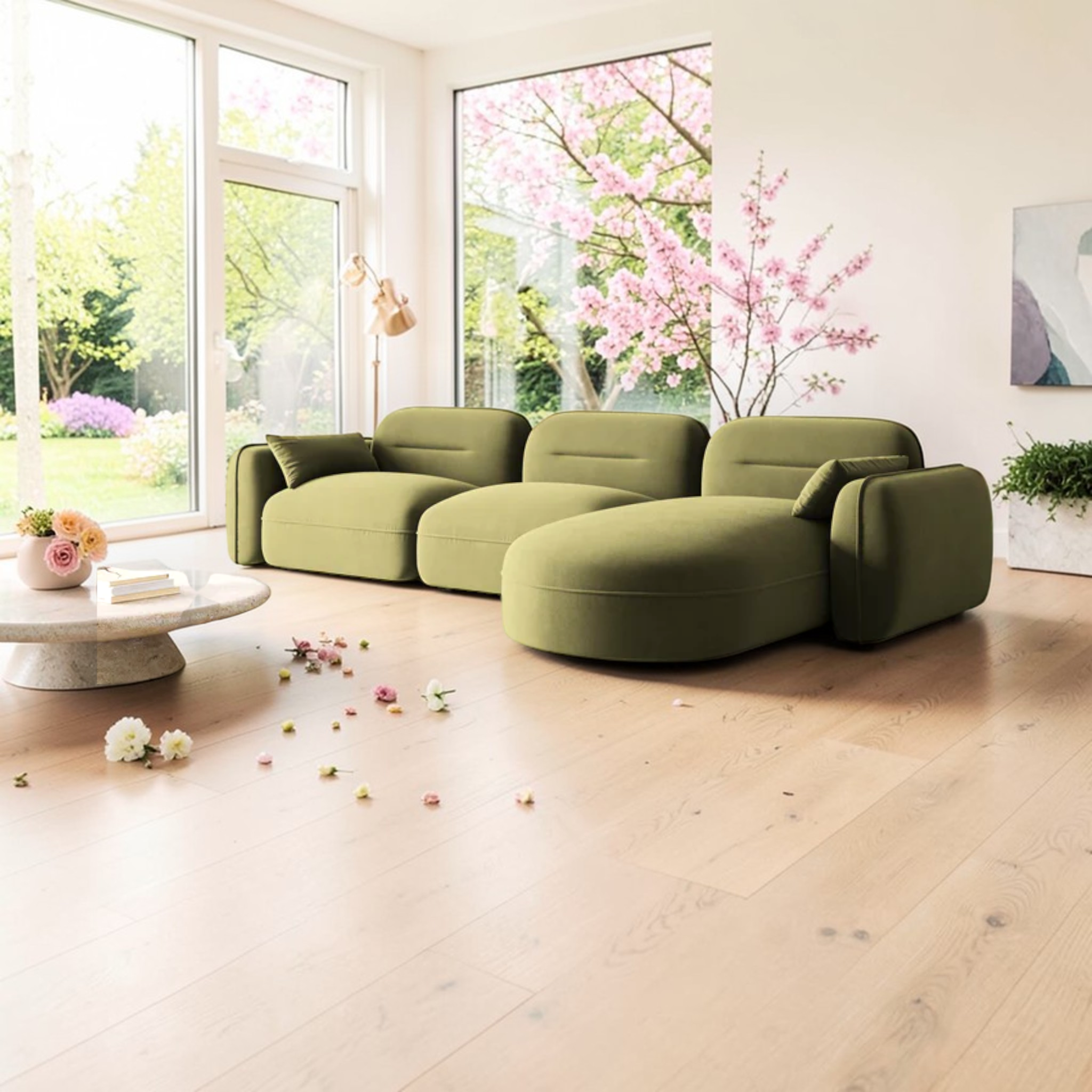 Green sectional sofa in a bright living room with large windows and cherry blossoms outside.
