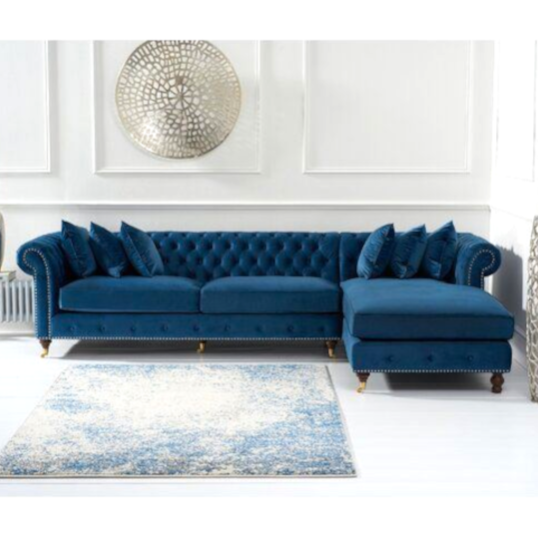 Blue tufted sectional sofa in a living room setting with a decorative rug and wall art.