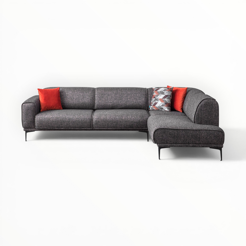 Gray sectional sofa with red and patterned cushions on a white background