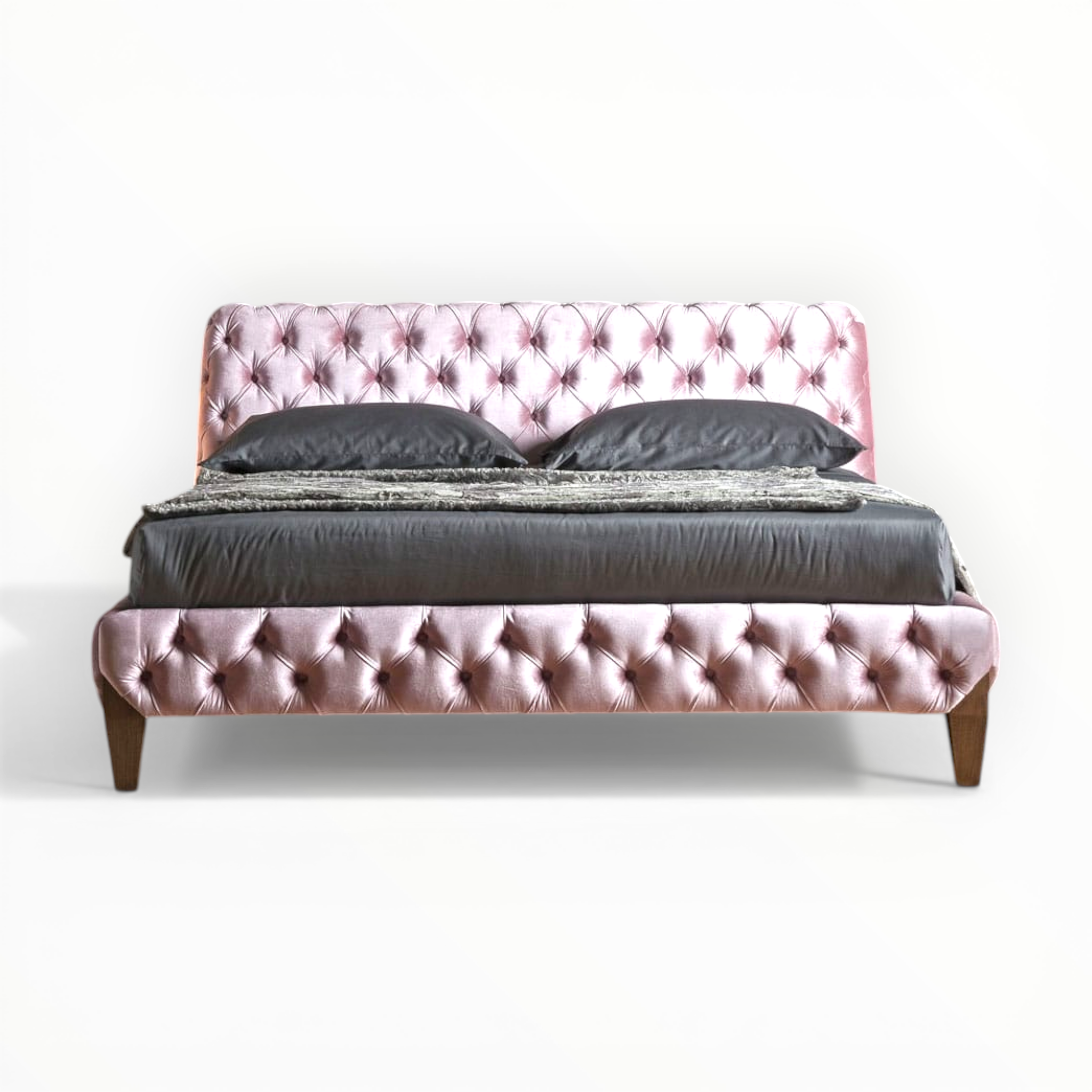 Pink tufted bed with dark bedding on a white background