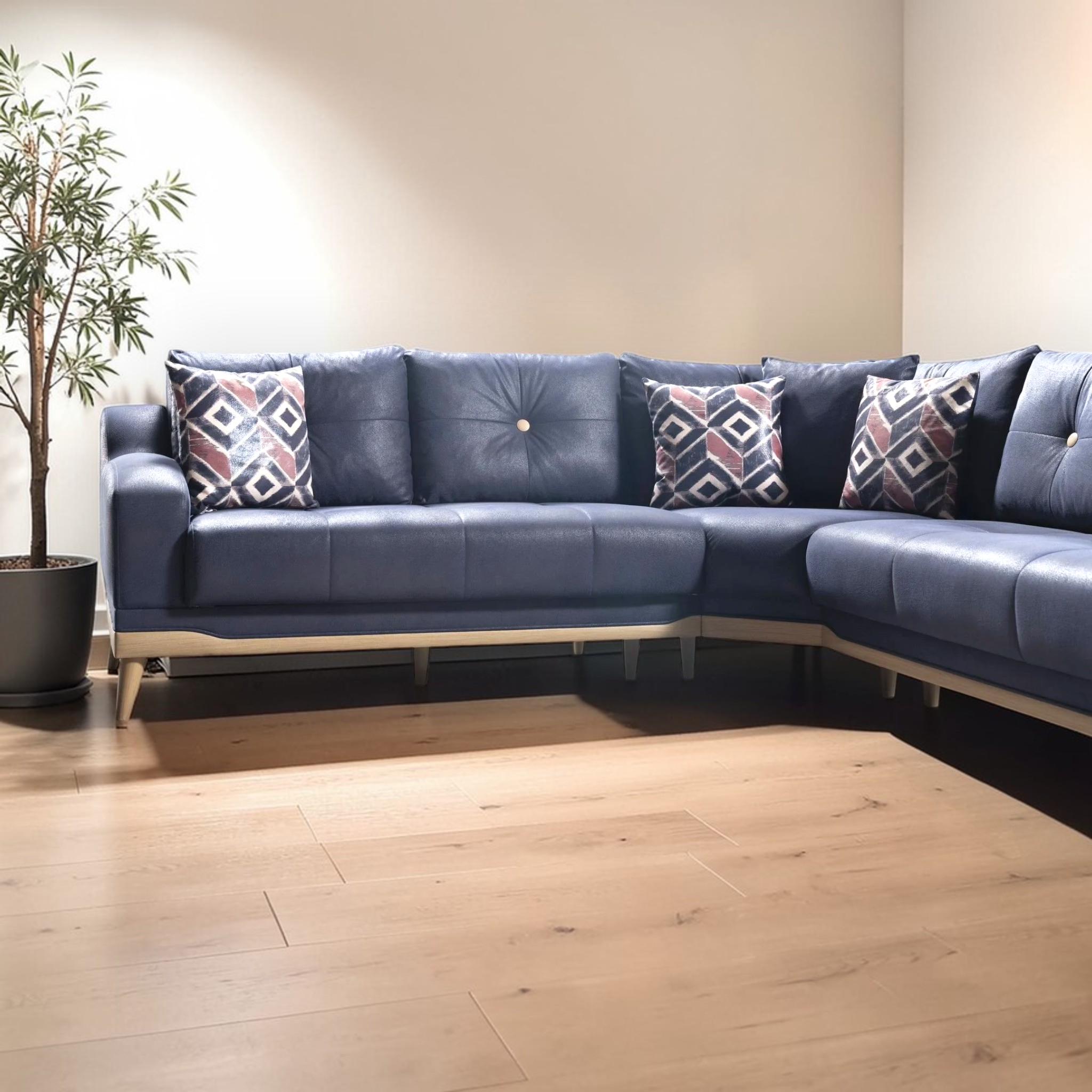 Blue sectional sofa with patterned cushions in a room with wooden flooring and a plant.