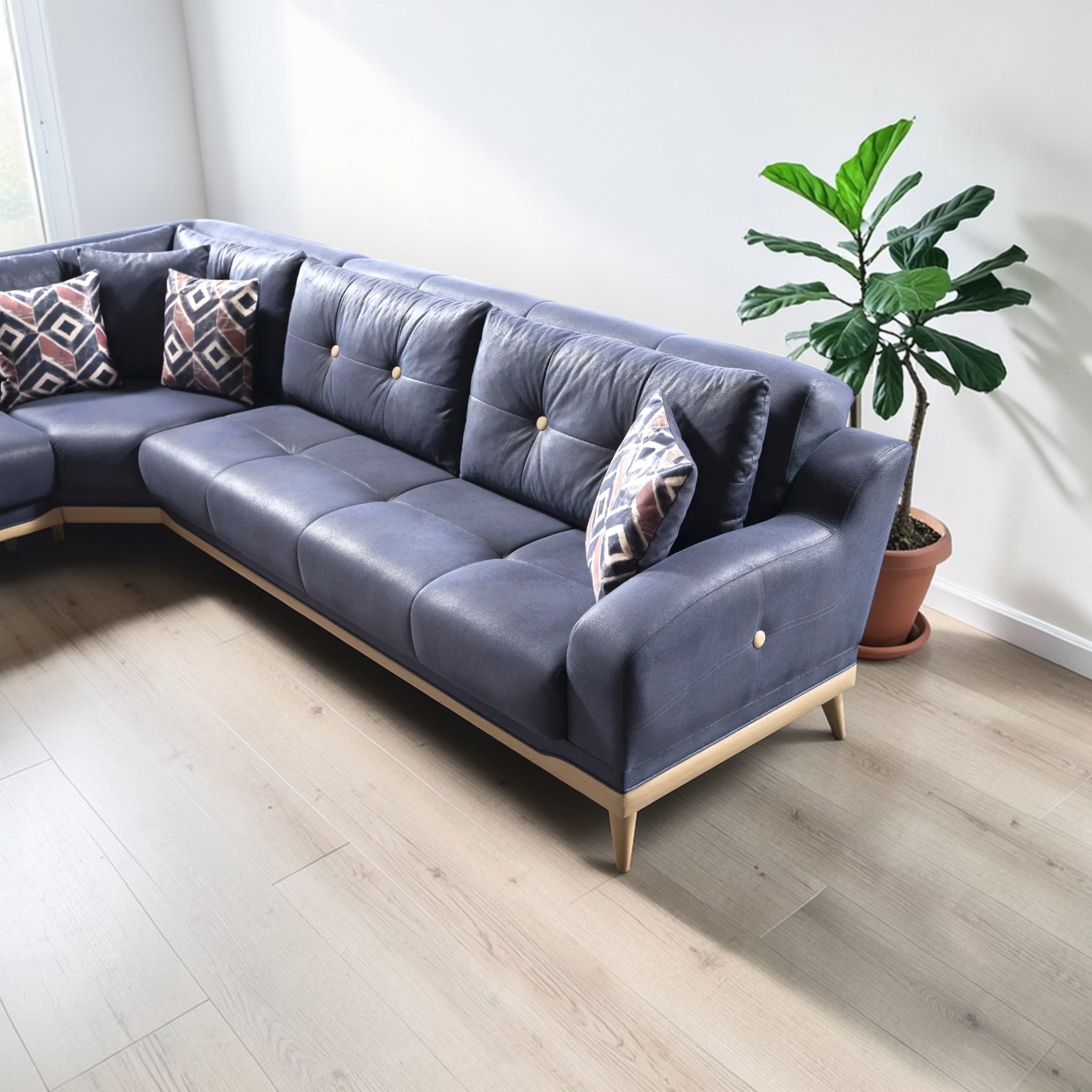 Gray sectional sofa with patterned cushions in a room with a plant.