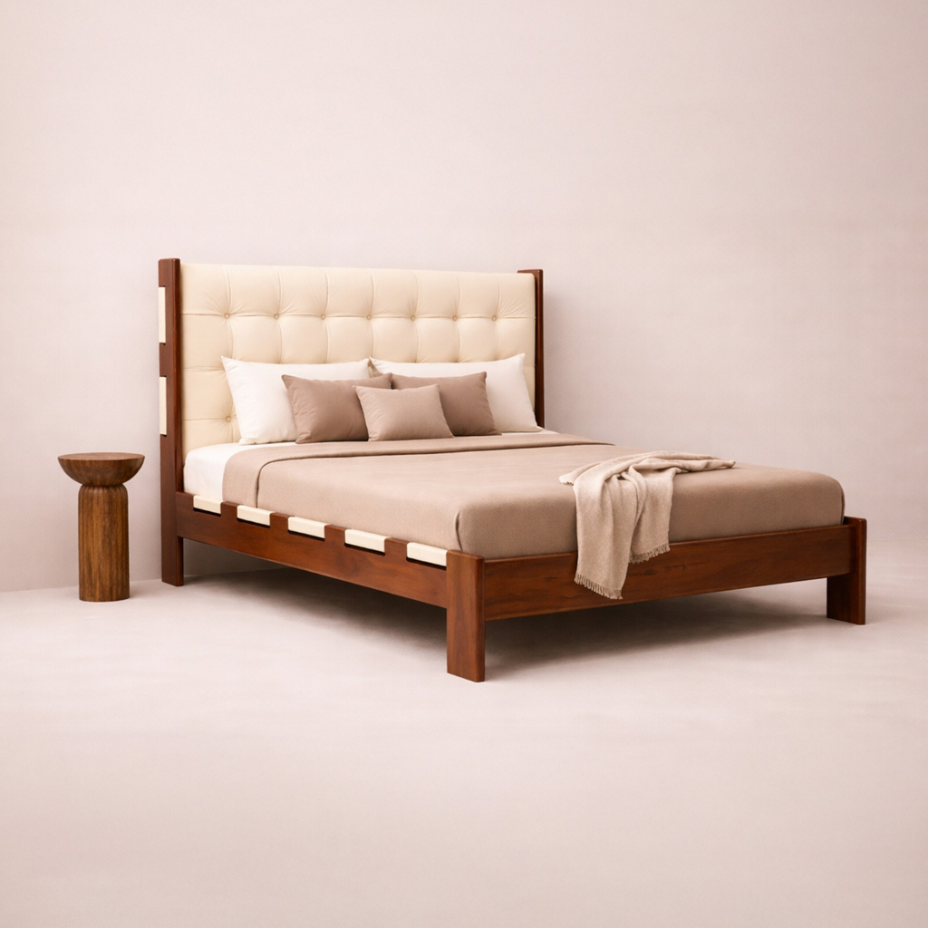 Wooden bed with beige bedding and pillows against a plain wall.