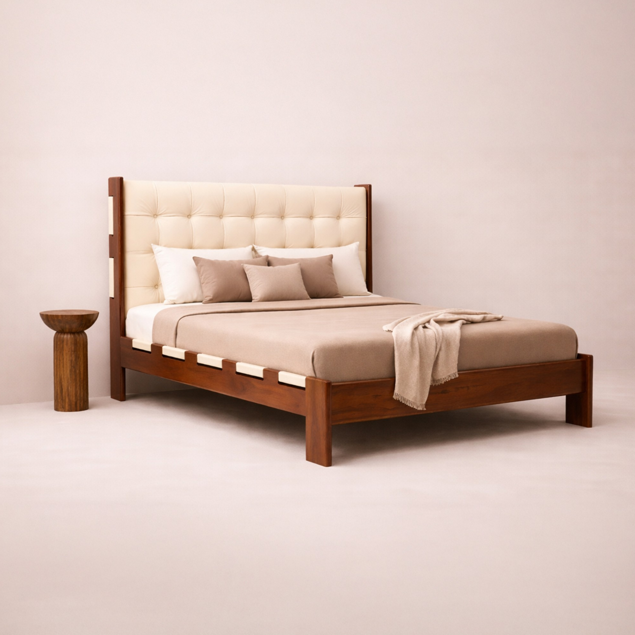 Wooden bed with beige bedding and pillows against a plain wall.