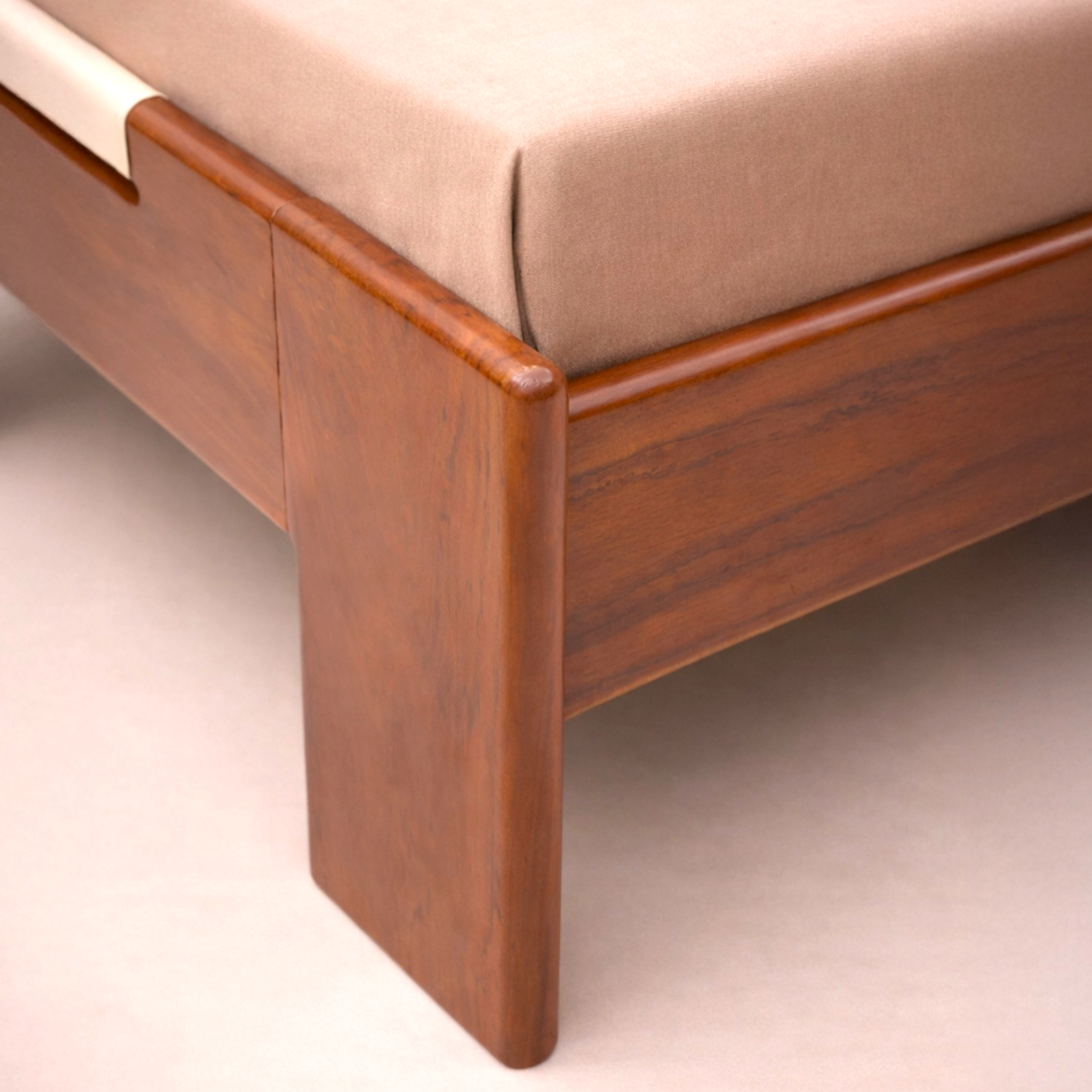 Wooden bed frame with beige mattress on a plain background