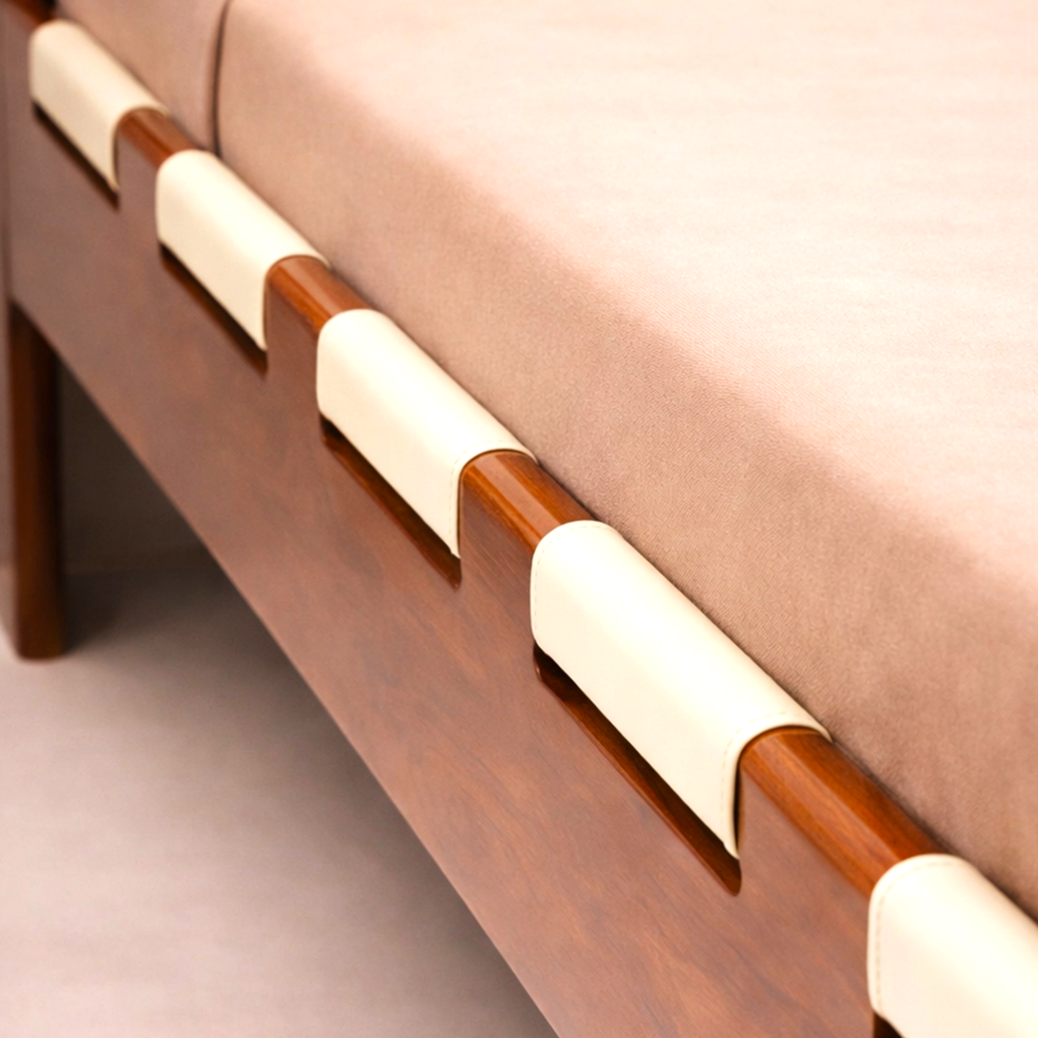 Wooden bed side panel with white cushioned ends against a beige background