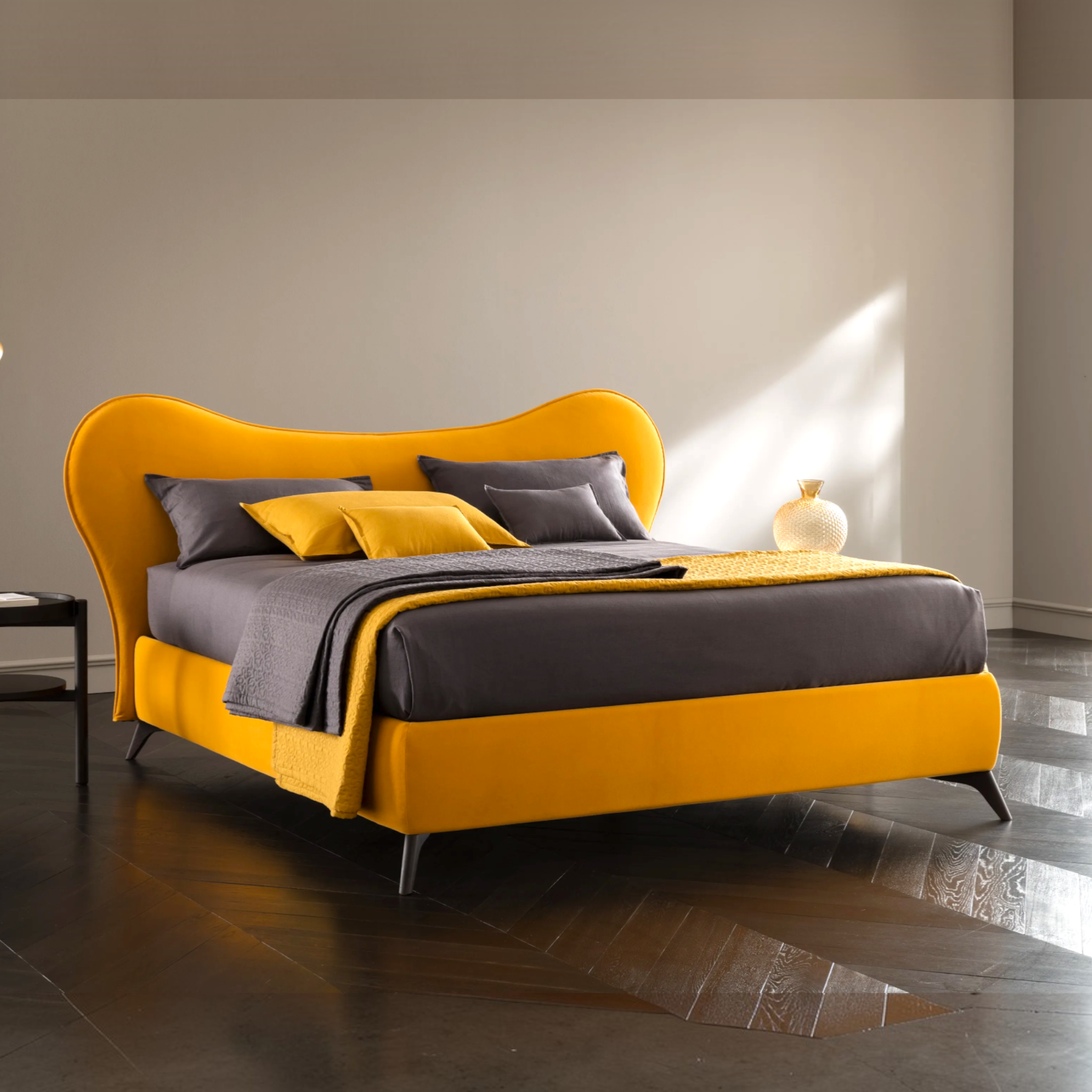 Yellow and gray bed in a modern room with a side table and lamp.