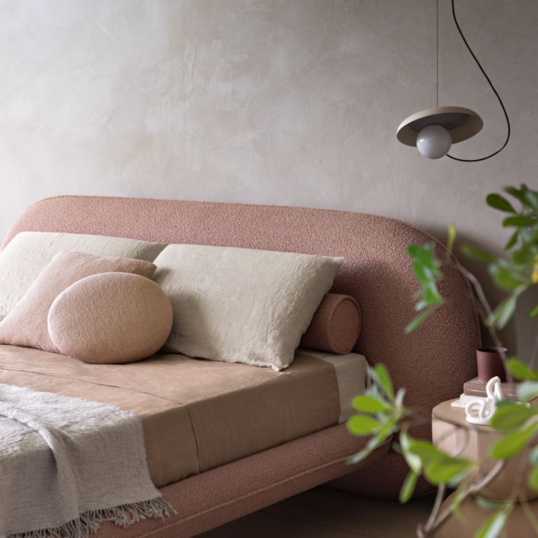 Pink upholstered bed with pillows in a softly lit room