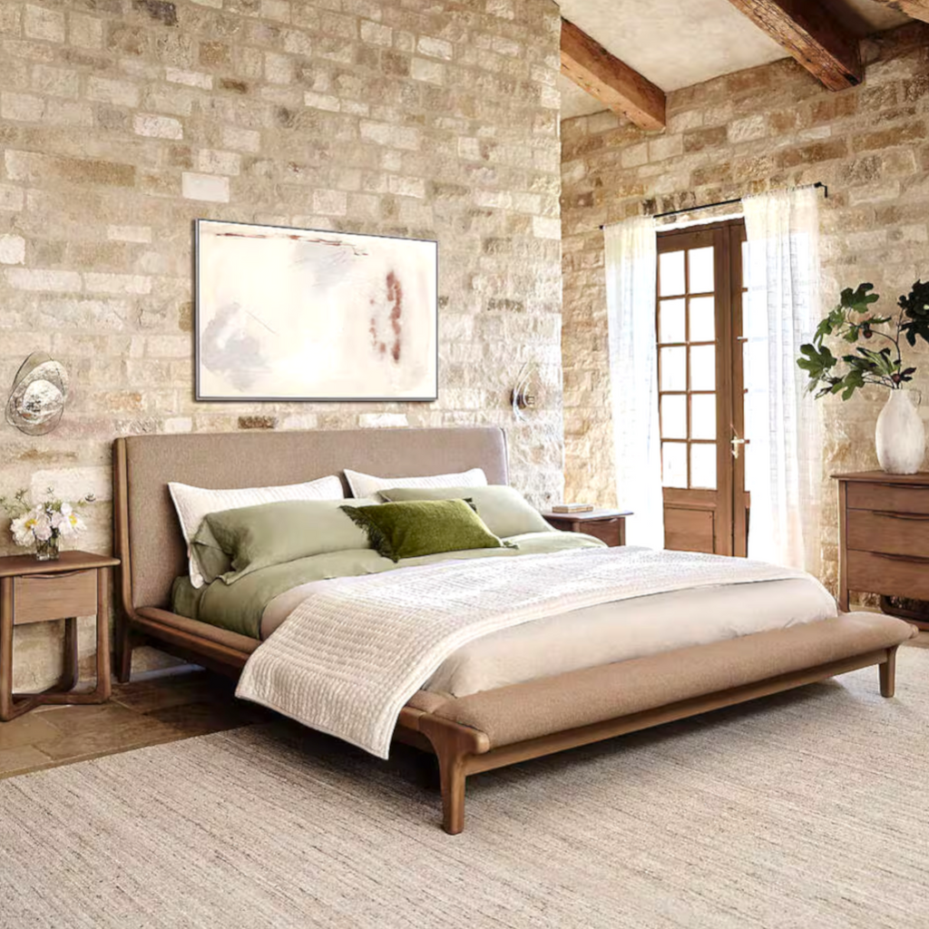 Bedroom with wooden bed, stone wall, and natural light