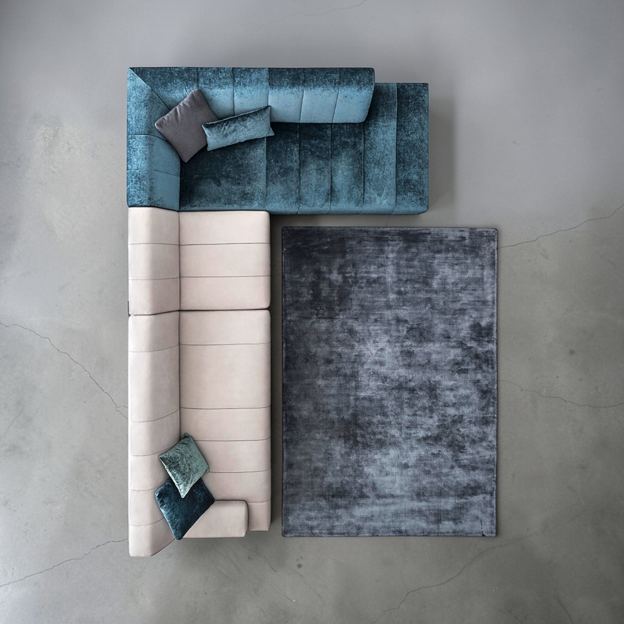 Modern sectional sofa with blue and beige colors on a concrete floor.