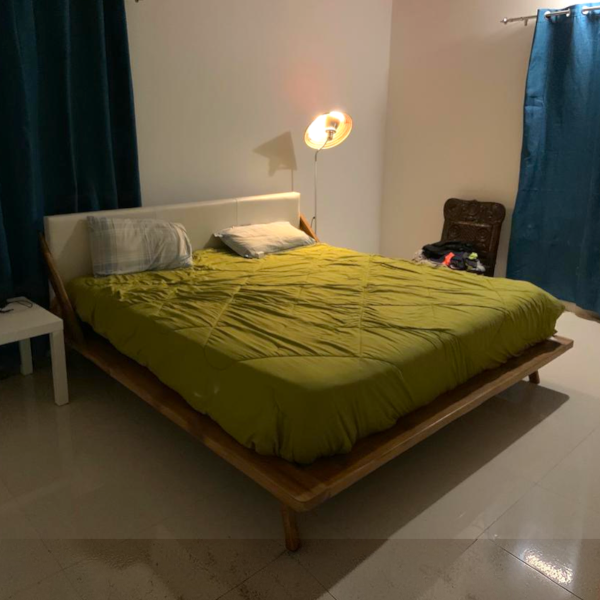 Bedroom with a bed covered in green bedding, a lamp, and a chair.