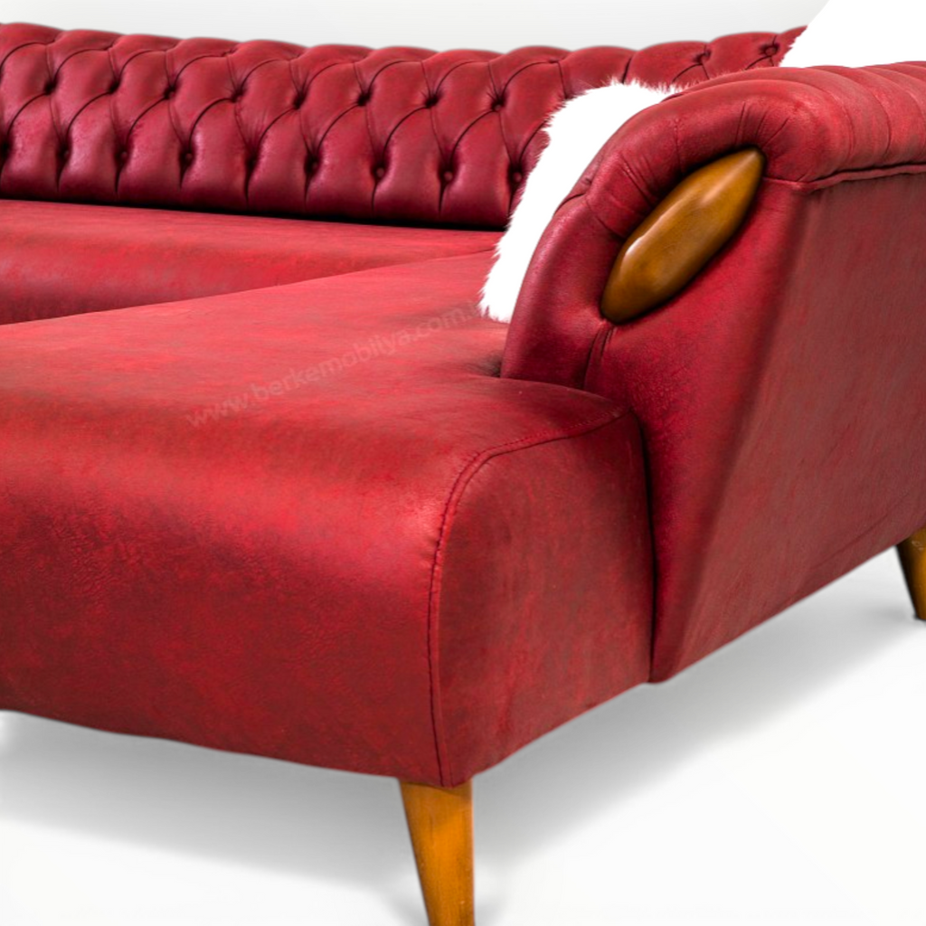 Red tufted sofa with wooden armrests on a white background