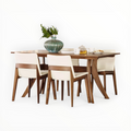 Dining table set with wooden chairs and a vase on a white background