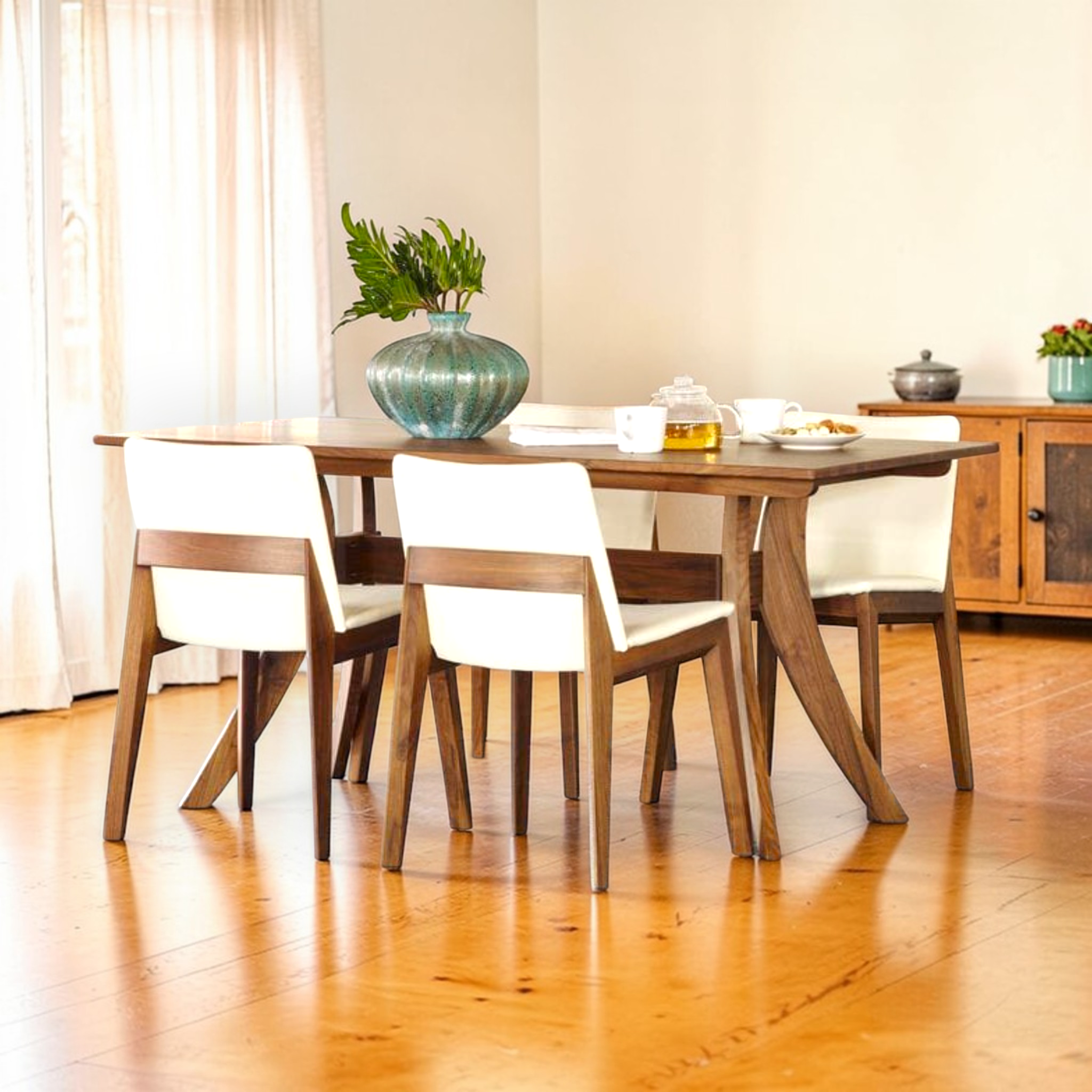 Dining room with wooden table and chairs, plants, and a cabinet.